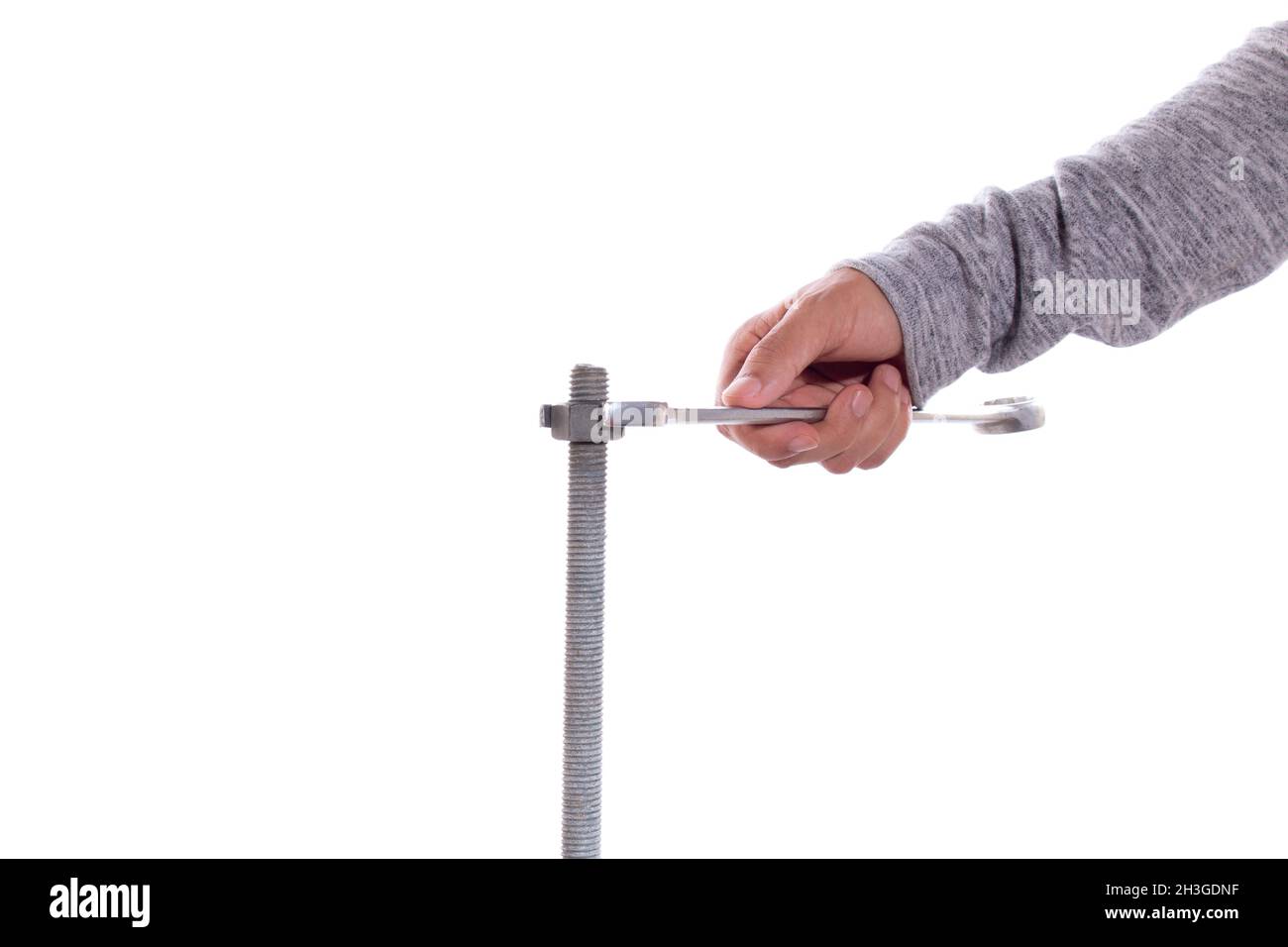 Man's Hand zieht eine Mutter mit einem Schraubenschlüssel, isoliert auf weißem Hintergrund. Stockfoto