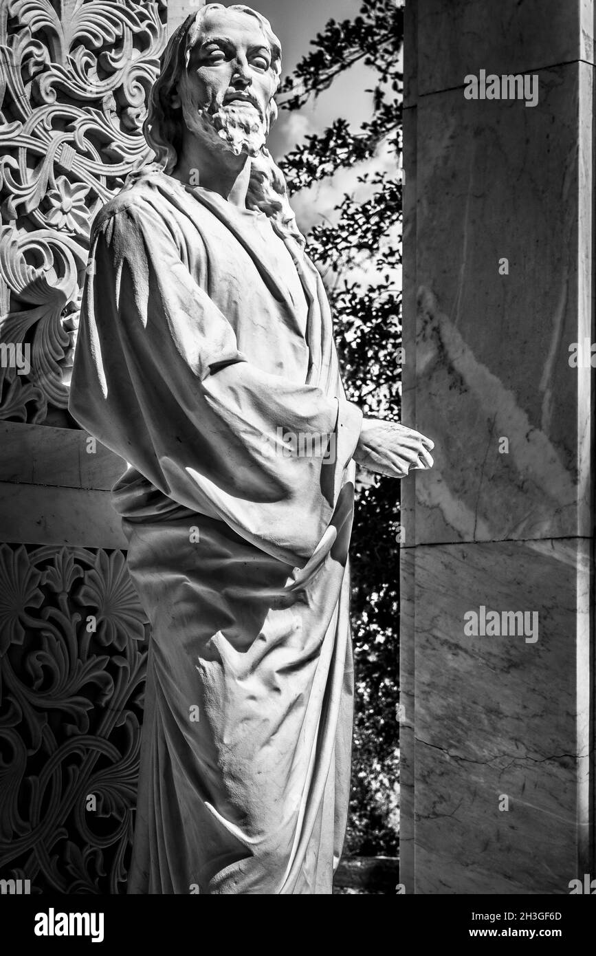 Graustufenaufnahme der Steinstatue eines Mannes auf dem Friedhof an einem sonnigen Tag Stockfoto