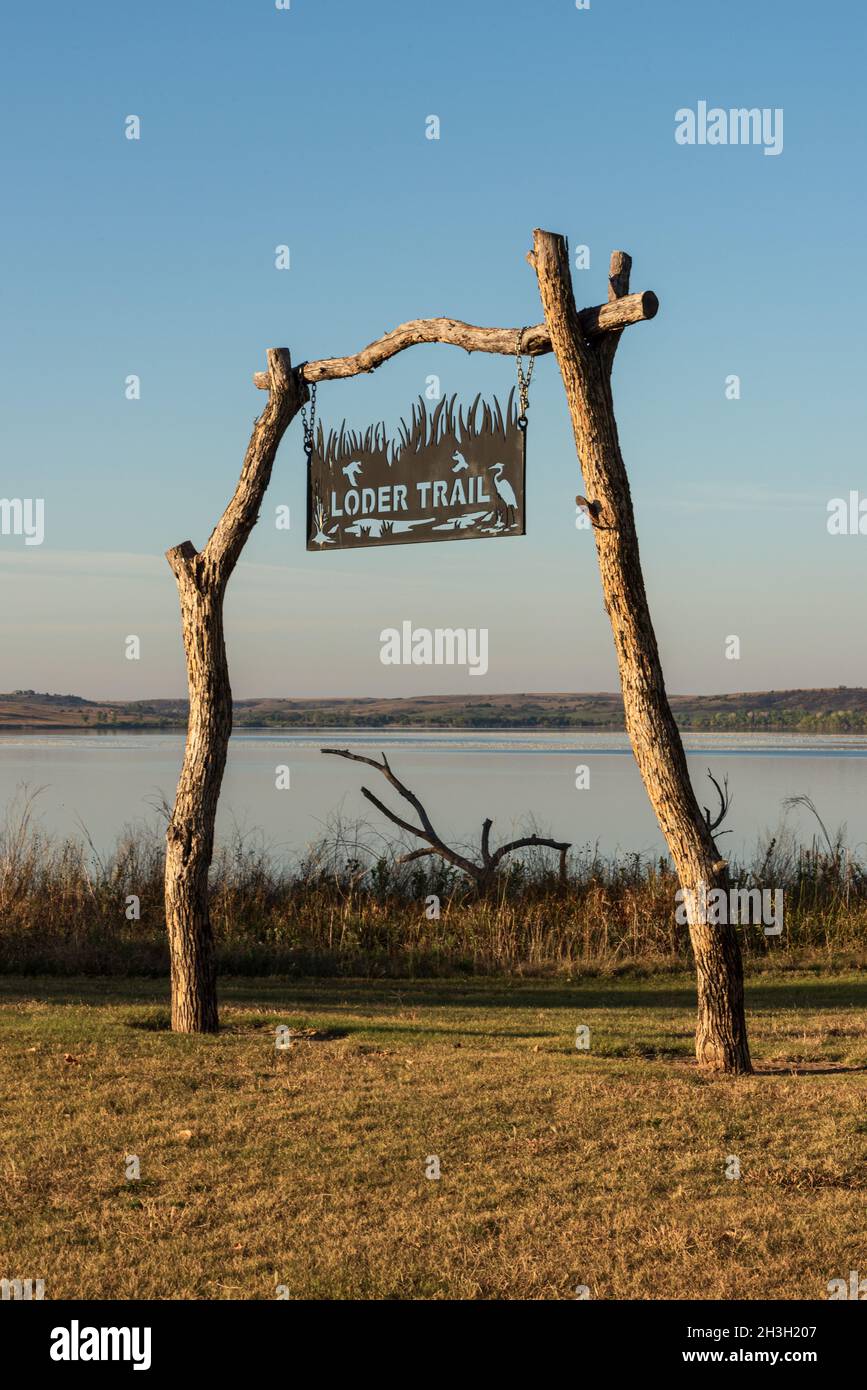 Ein handgemachtes Metallschild, das an Pfosten hängt, und eine Querlatte aus Baumstämmen markieren den Wegweiser des Loder Trail. Stockfoto Ein handgemachtes Metallschild, das an Pfosten hängt, und eine Querlatte aus Baumstämmen markieren den Wegweiser des Loder Trail. Stockfoto