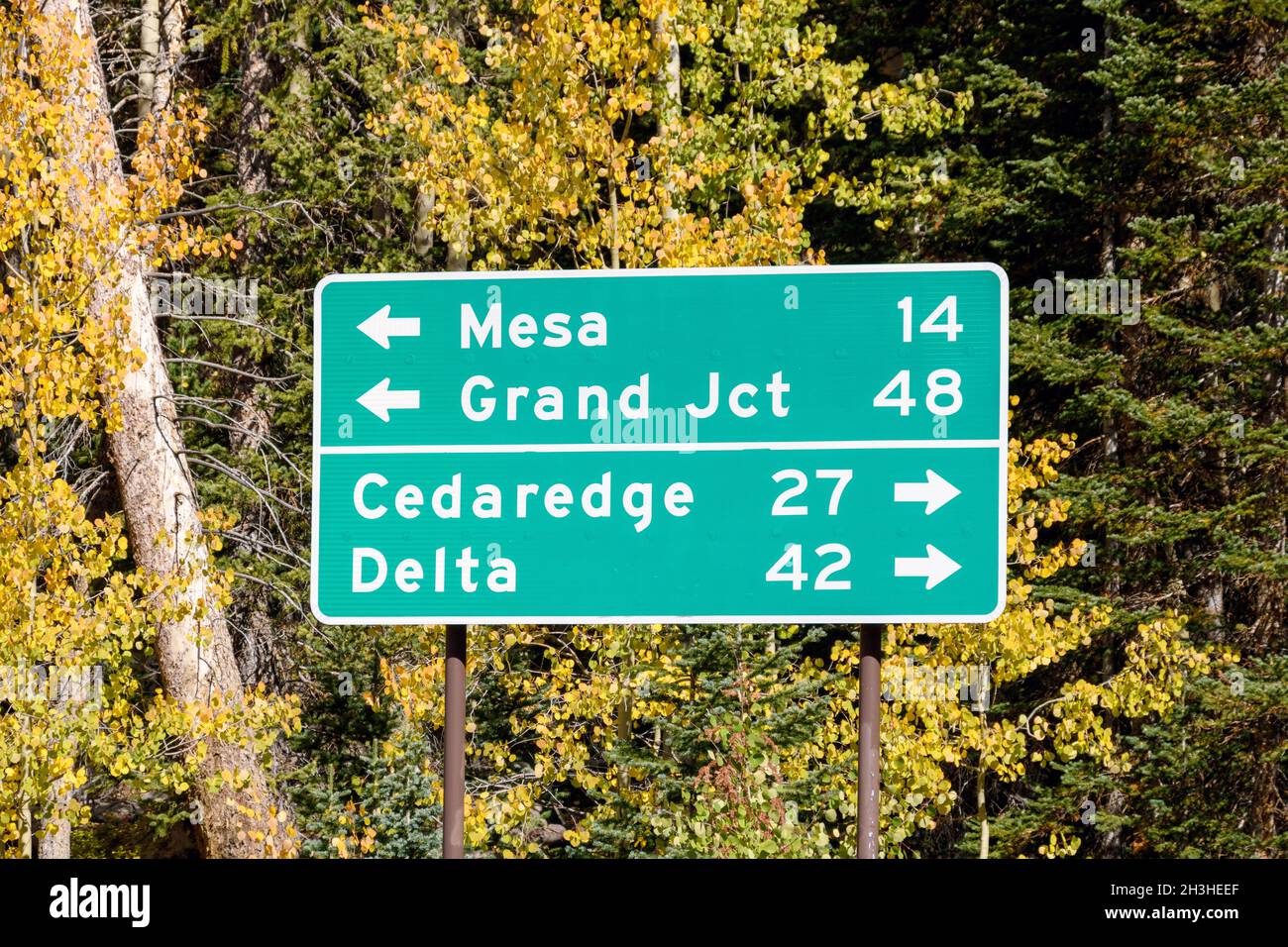 Rechteckig geformtes grünes Wegweiser mit weißem Schriftzug. Richtung und Entfernung nach Mesa, Grand Junction, Cedardge und Delta in Grand Mesa Nation Stockfoto