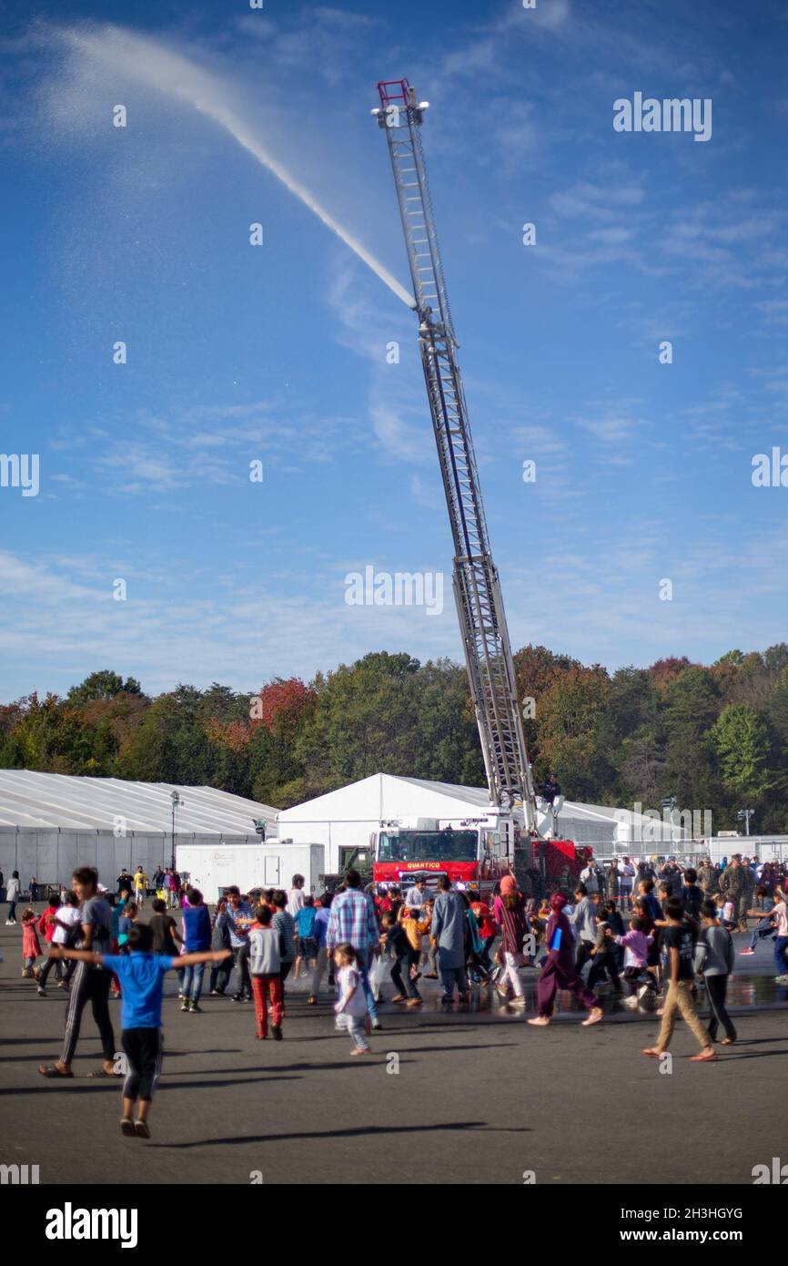 Quantico Fire Department demonstriert afghanischen Gästen den Luftschlauch während eines statischen Feuerwehrfahrzeuges, um sie mit der Feuerwehr auf der Marine Corps Base Quantico, Virginia, 25. Oktober 2021 vertraut zu machen. Das Verteidigungsministerium stellt über das Northern Command der USA und zur Unterstützung des Heimatschutzministeriums so schnell wie möglich Transport, vorübergehende Unterbringung, medizinische Vorsorgeuntersuchungen und allgemeine Unterstützung für mindestens 50,000 afghanische Evakuierte in geeigneten Einrichtungen, in permanenten oder temporären Strukturen bereit. Diese Initiative bietet afghanischen Evakuierten eine essentiellen Stellenwert Stockfoto