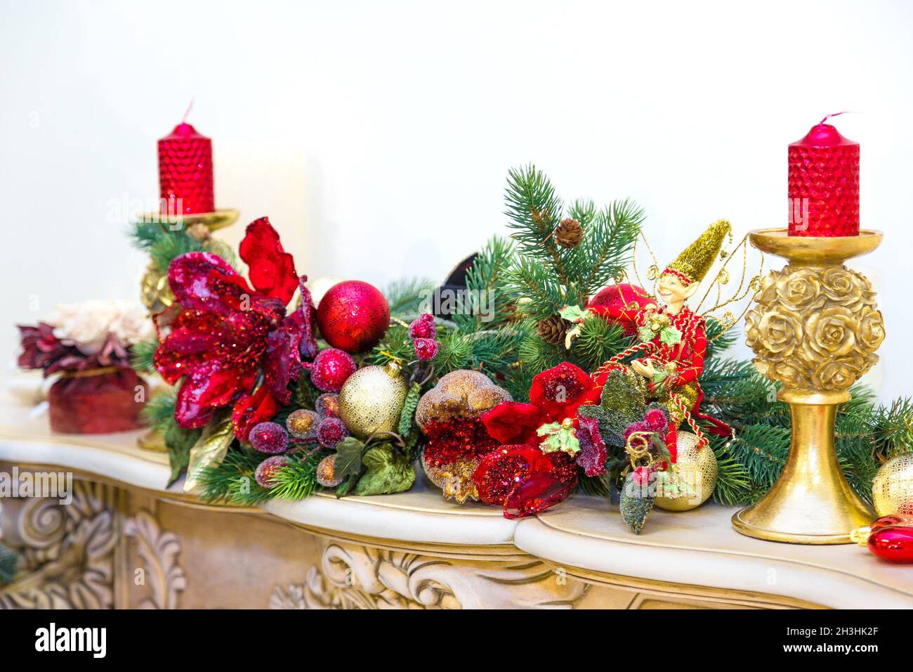 Ein Kaminmantel ist zu Weihnachten mit Girlande, Lichtern, einem Bogen und anderen Dekorationen geschmückt. Stockfoto