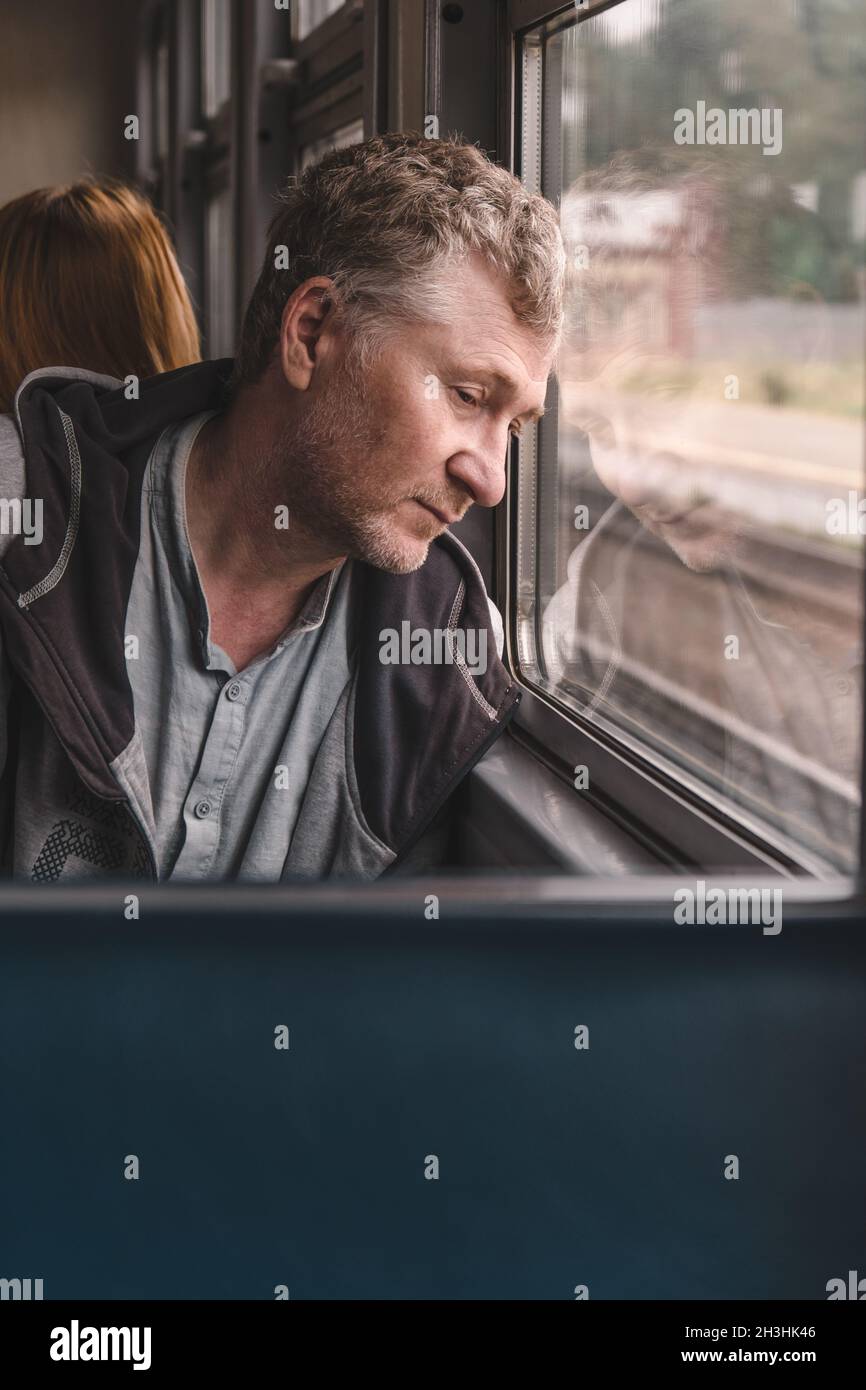 Frustrierter Mann mittleren Alters sitzt in einem Elektroauto in der Nähe des Fensters. Probleme im Leben und im Geschäft. Psychische Gesundheit. Stockfoto