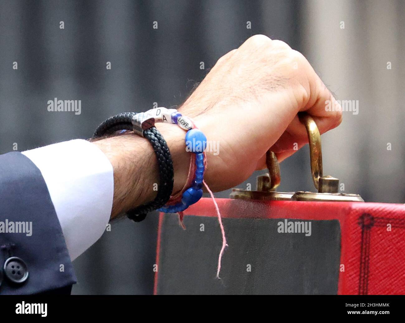 London, Großbritannien. Oktober 2021. Ein LIEBESZAUBER auf dem Armband von Rishi Sunak, dem Schatzkanzler, mit der roten Budget-Box vor der Downing Street Nummer 11, bevor er mittags seine Haushaltsrede im Unterhaus hält. Budget Day, Downing Street, Westminster, London, 27. Oktober, 2021. Kredit: Paul Marriott/Alamy Live News Stockfoto