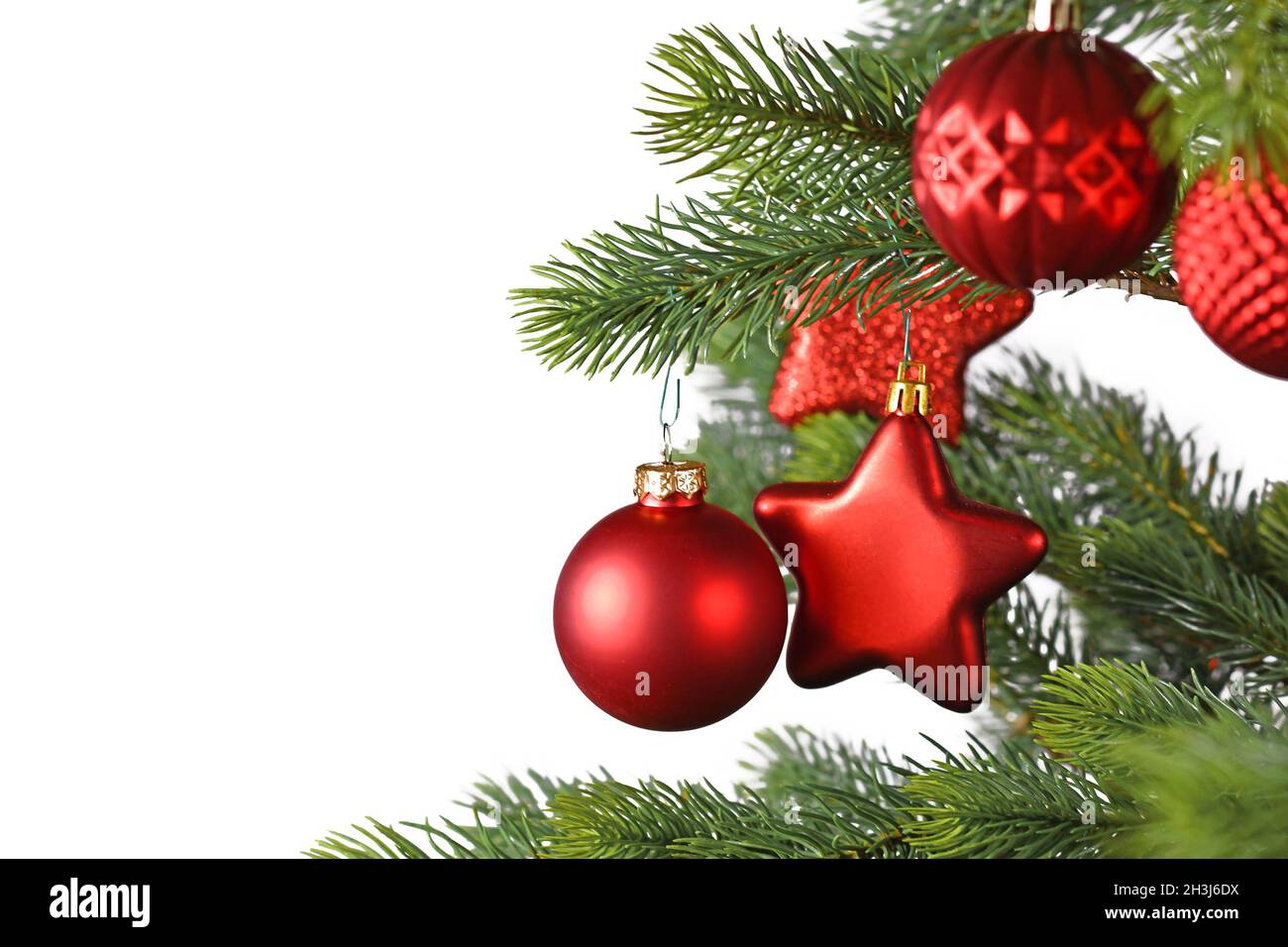 Rote Stern- und kugelförmige Weihnachtskugeln auf geschmücktem Weihnachtsbaum auf weißem Hintergrund mit Kopierraum Stockfoto