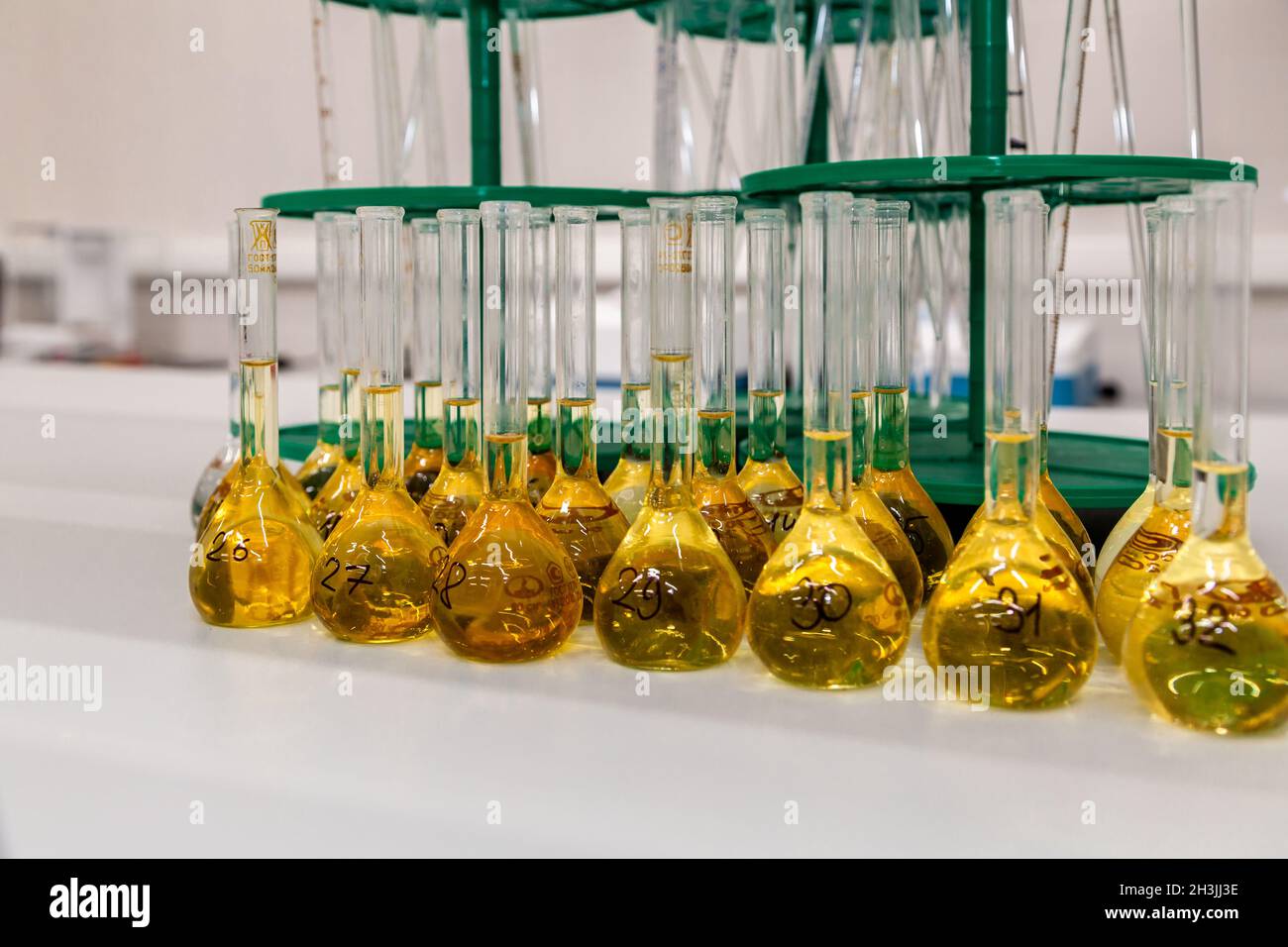 Eine lange Reihe von Glaskolben mit einer gelben Lösung auf einem Labortisch zu verschließen Stockfoto