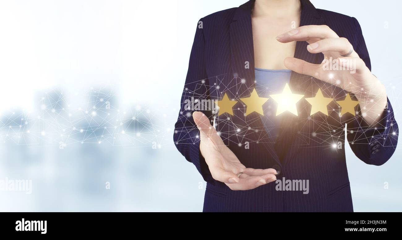 Bewertung, Bewertung, Zufriedenheit. Zwei Hand halten virtuelle holographische fünf-Sterne-Symbol mit hellen unscharfen Hintergrund. Customer Experience Konzept Stockfoto