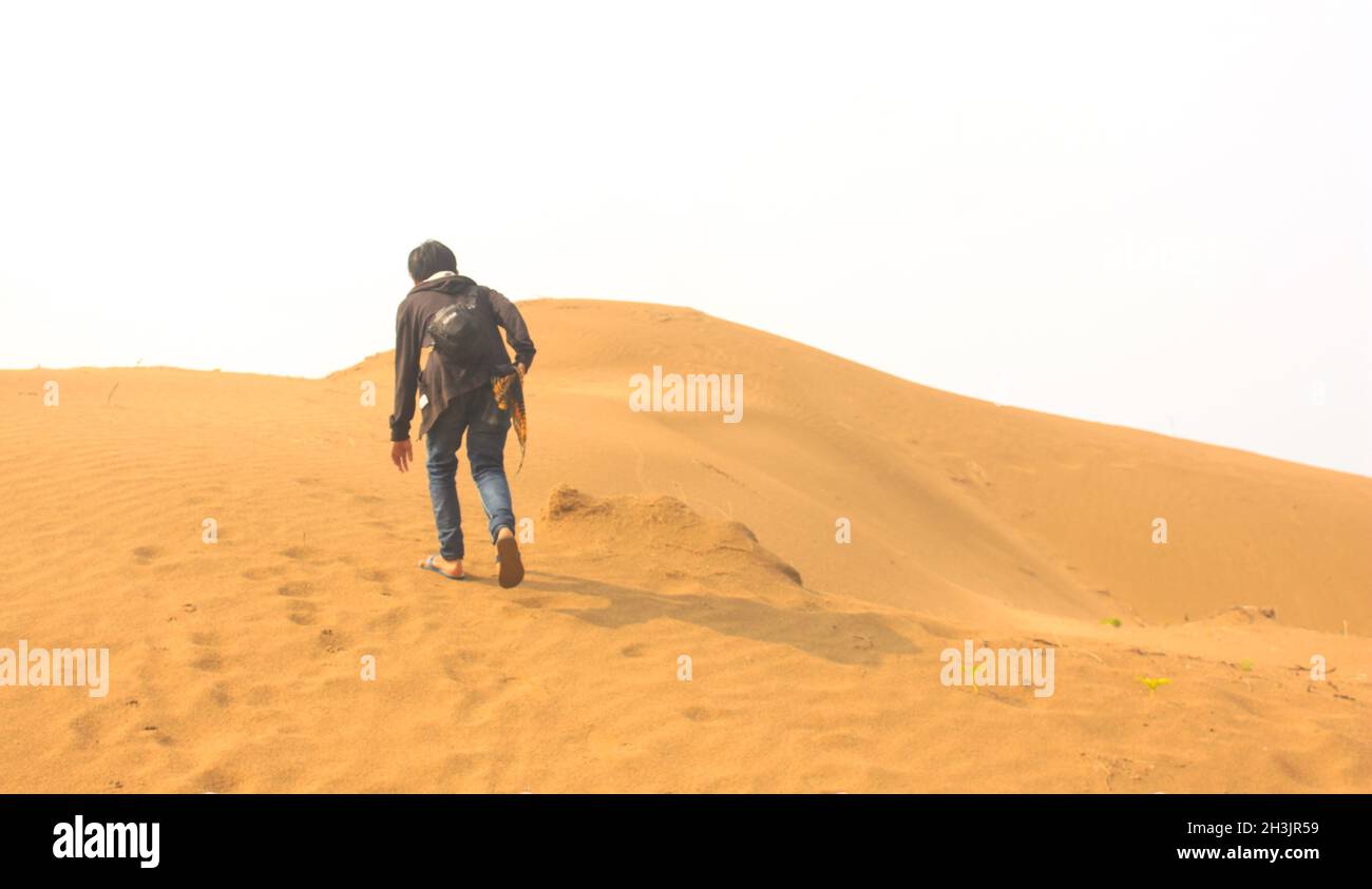 Ein Mann, der auf einer Sanddüne in einer Wüste läuft Stockfoto