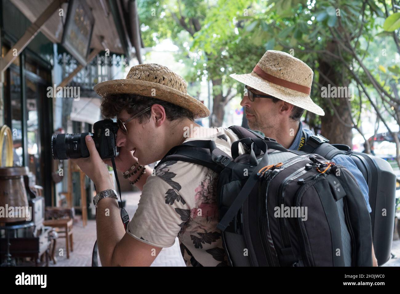 Seitenansicht von zwei Rucksacktouristen, die ein Foto machen und Touristenattraktionen in Bangkok besuchen Stockfoto