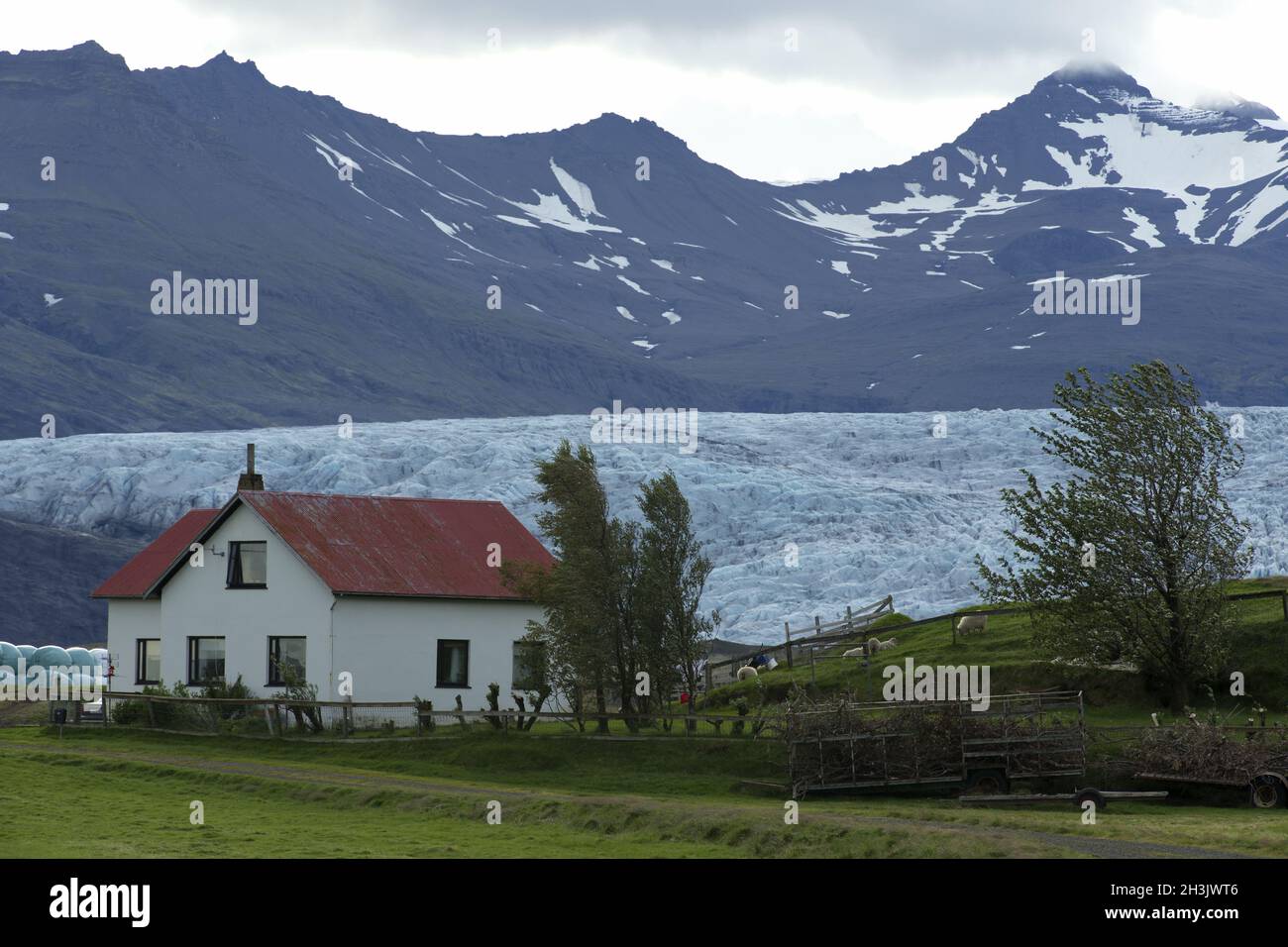 Einsames Haus auf Felsen an der Unterseite des Berges, Island. Stockfoto