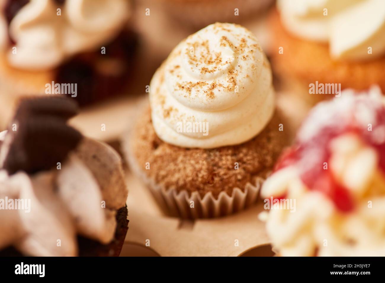 Cupcake mit Schlagsahne und Dekoration neben anderen bunten Cupcakes Stockfoto