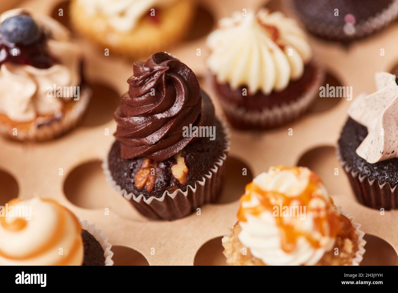 Viele verschiedene Cupcakes mit Creme zur Auswahl in einer Bäckerei Stockfoto