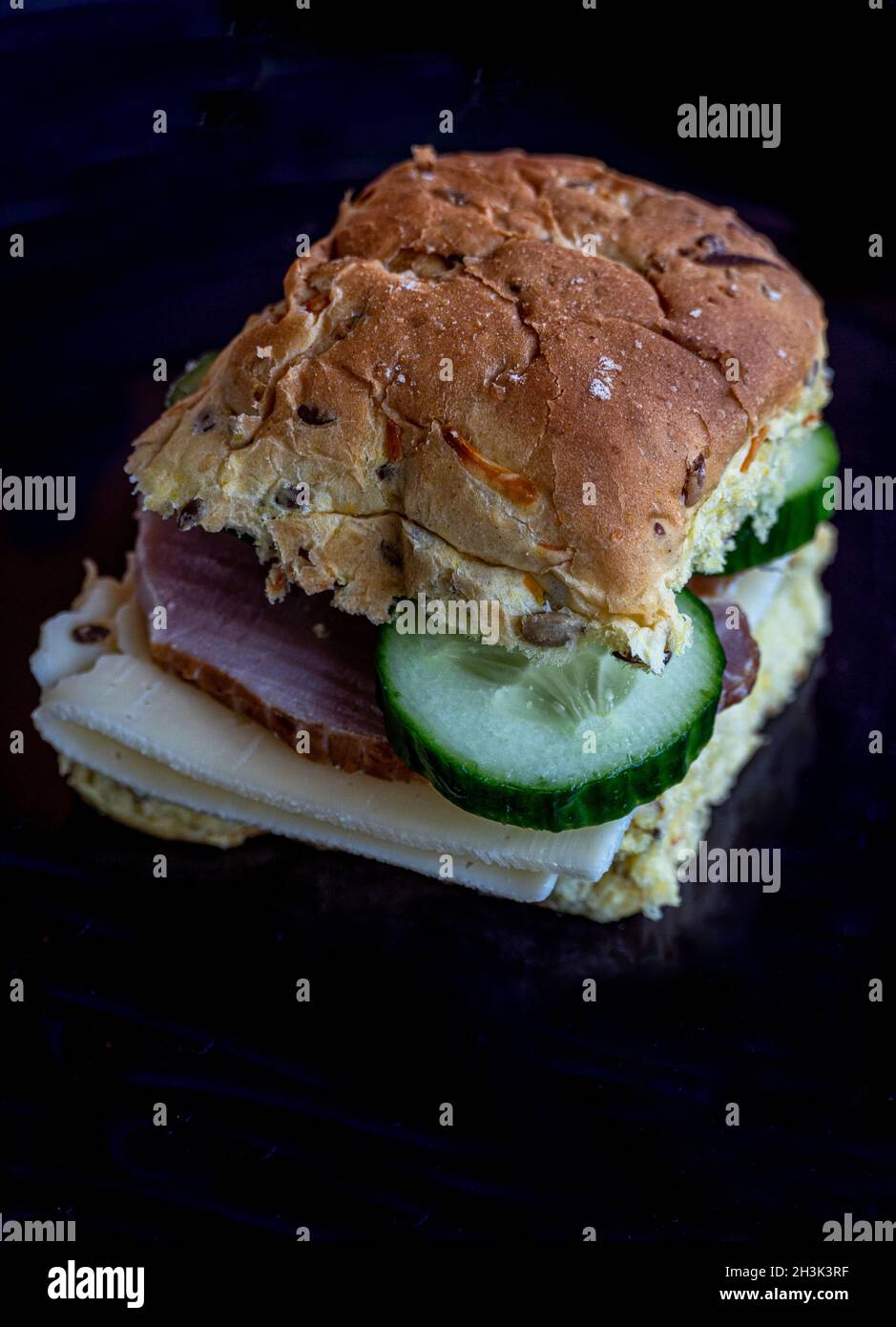 Typisch dänisches Sandwich mit geräuchertem Schinken und Käsegurken auf einem schwarzen Teller. Dänemark, Europa Stockfoto