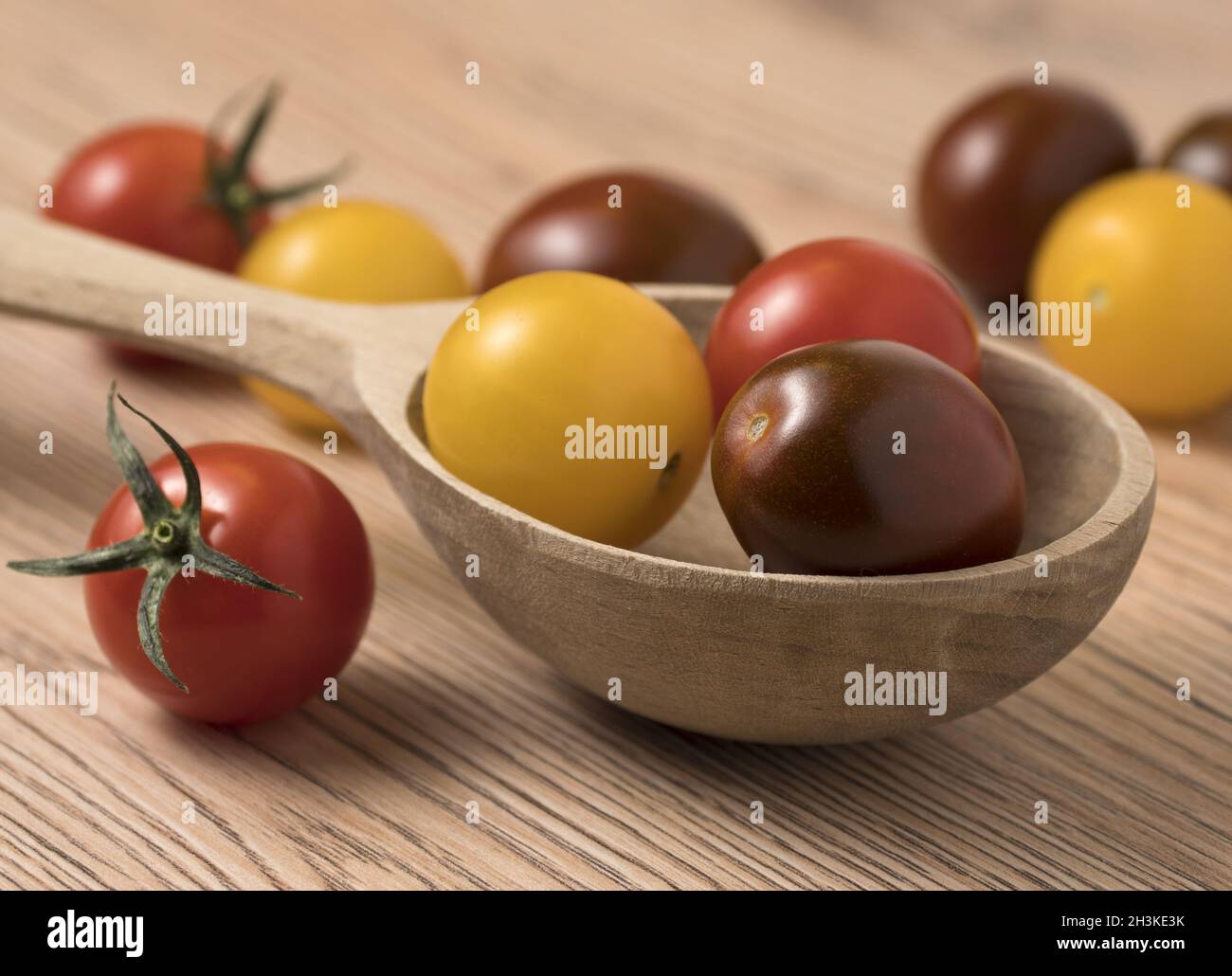 Kirschtomaten in verschiedenen Farben in Holzlöffel. Stockfoto