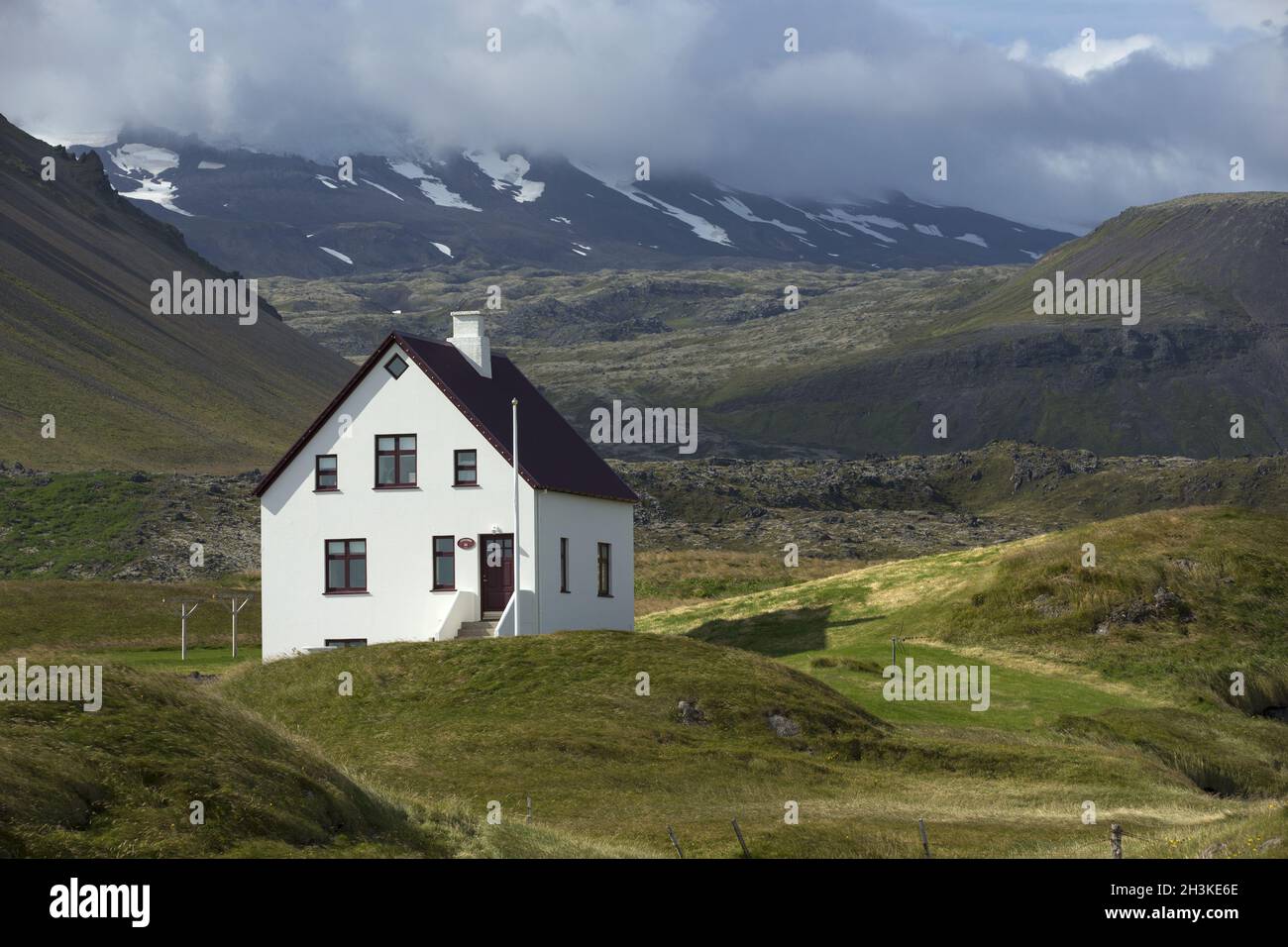 Einsames Haus auf Felsen an der Unterseite des Berges, Island. Stockfoto