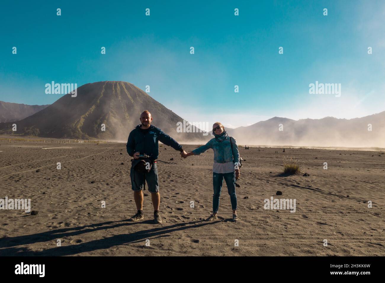 Fröhliche Paare, die in einer vulkanischen staubigen Wüste in der Nähe des wunderschönen Mount Bromo in Ost-Java stehen Stockfoto