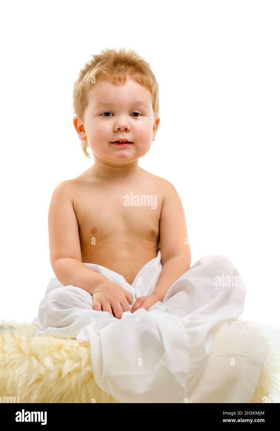 Niedlicher kleiner blonder Junge, drei Jahre alt, sitzt auf weißem Hintergrund. Stockfoto