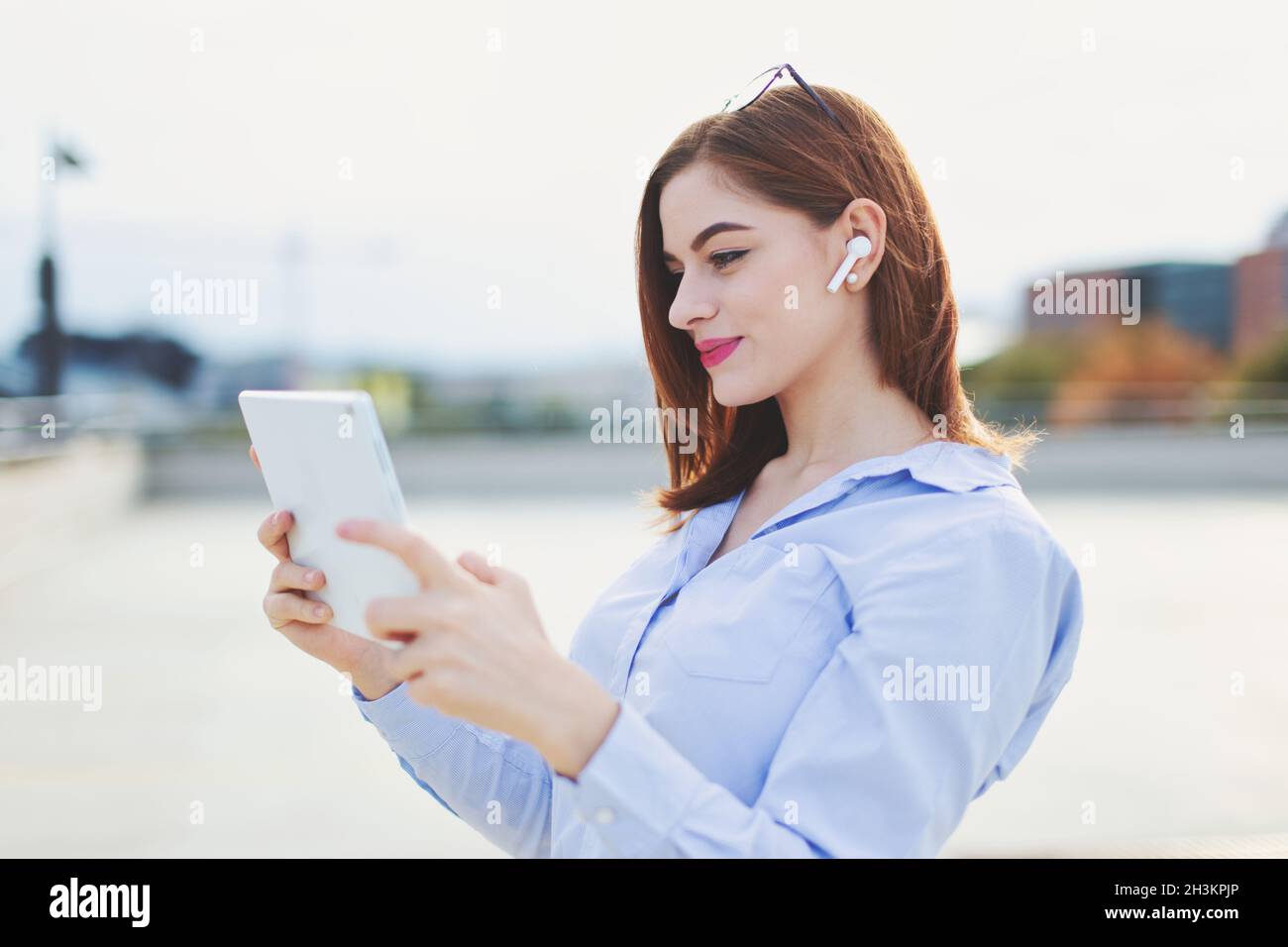 Junge moderne Geschäftsfrau arbeitet auf Tablet in der Stadt im Freien Stockfoto