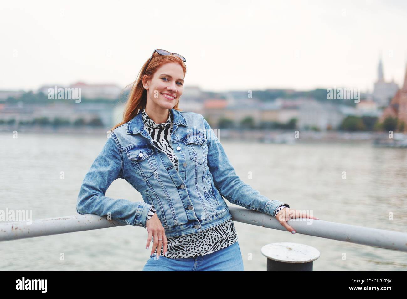 Glückliche junge Rotschopf kaukasische Frau posiert am Flussufer Stockfoto