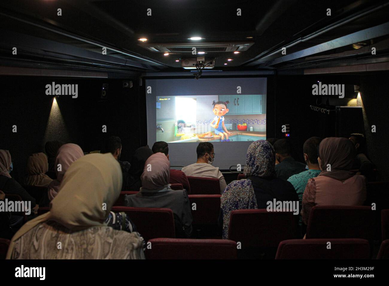 (211029) -- GAZA, 29. Oktober 2021 (Xinhua) -- Palästinenser sehen sich einen Film an, der auf einer weißen Leinwand gezeigt wird, die in einem Bus im nördlichen Gazastreifen aufgestellt ist, am 28. Oktober 2021. ZUM „Feature: Mobiles Kino ermöglicht den Bewohnern, Filme auf einer großen Leinwand in Gaza anzusehen“ (Foto: Rizek Abdeljawad/Xinhua) Stockfoto