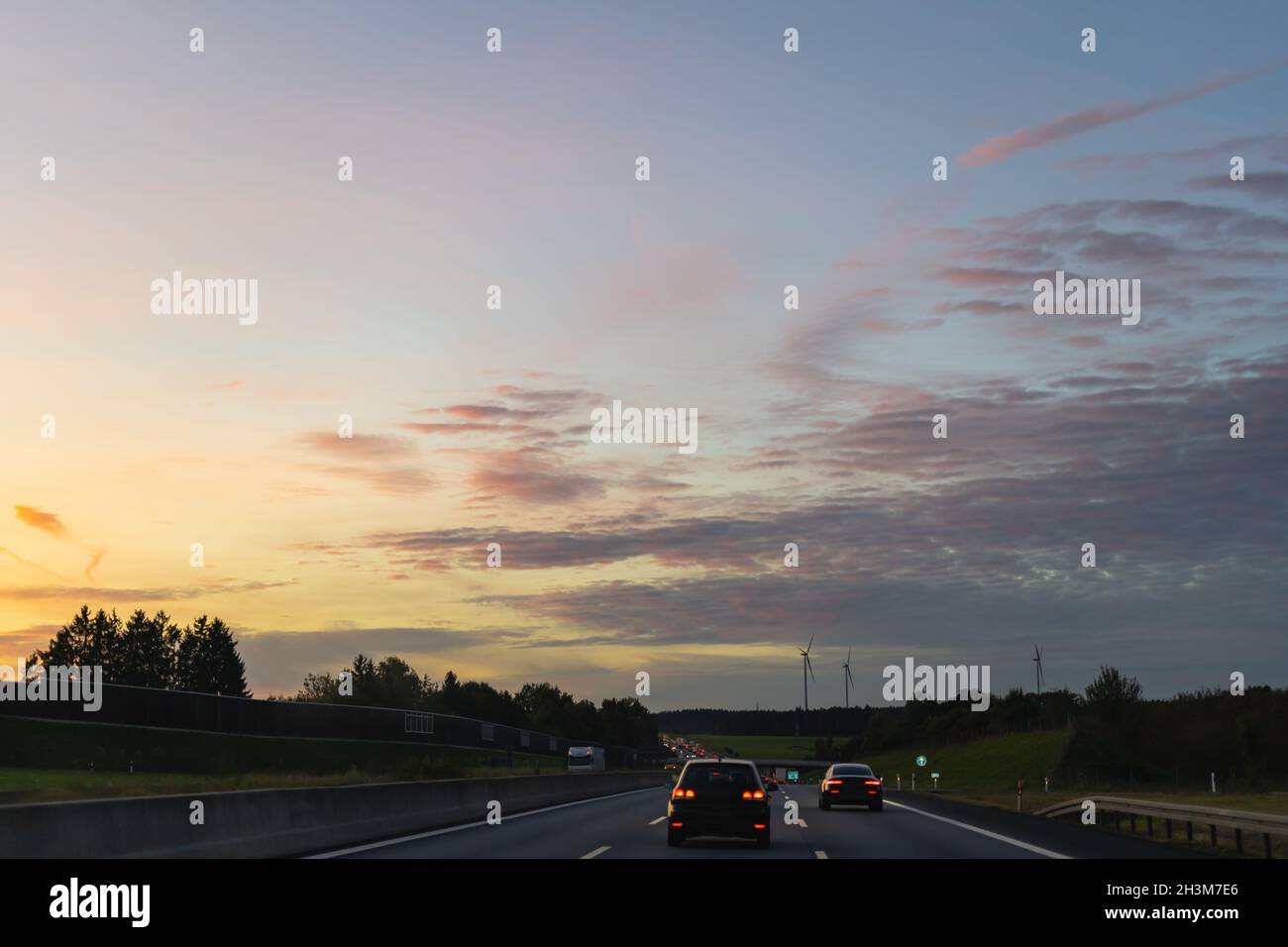 Verkehr auf der Autobahn.Deutsche Autobahn mit Fahrzeugen bei Sonnenuntergang. Stockfoto