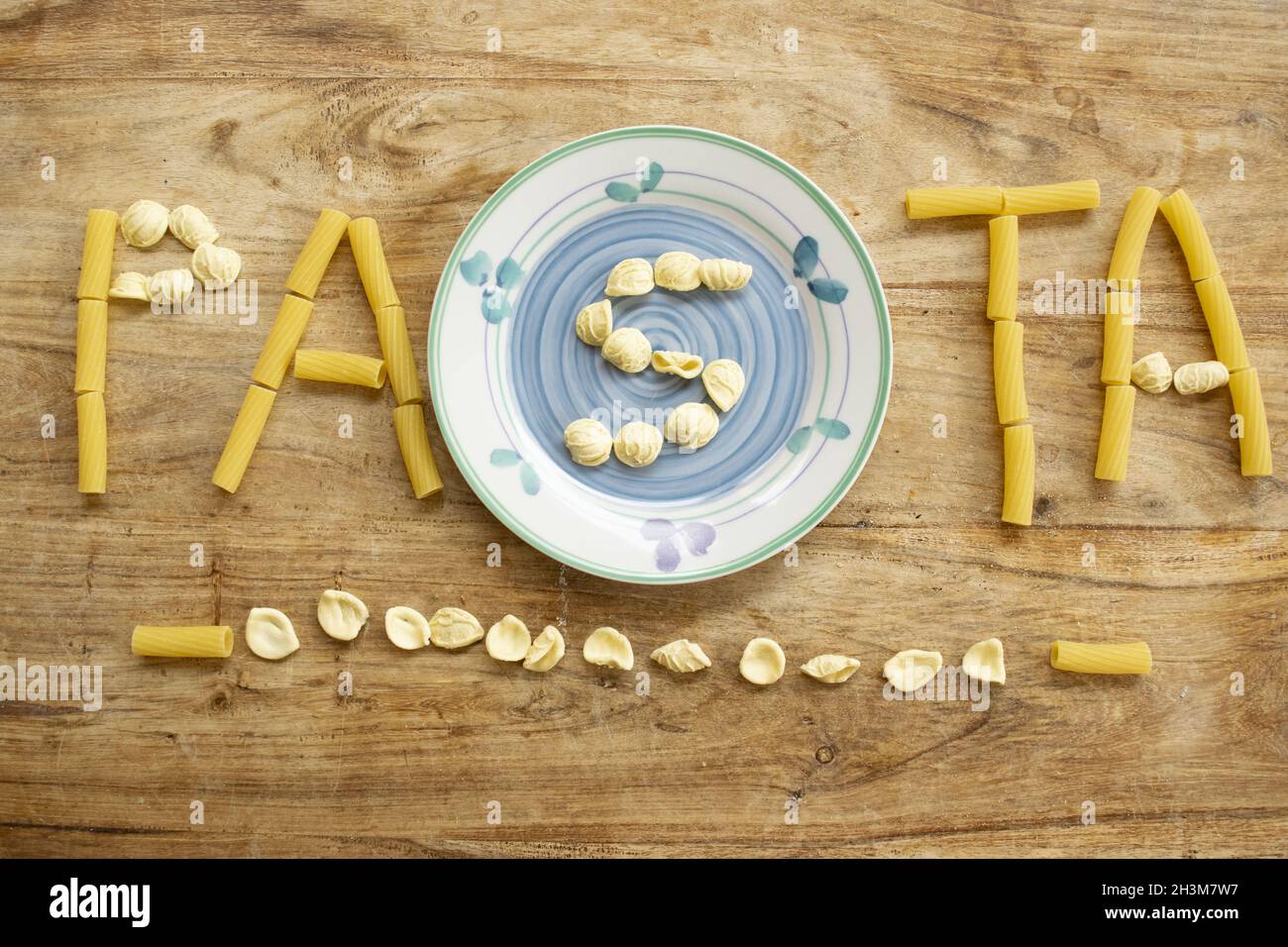Pasta-Wort mit Nudelkörnern auf Holzhintergrund geschrieben Stockfoto