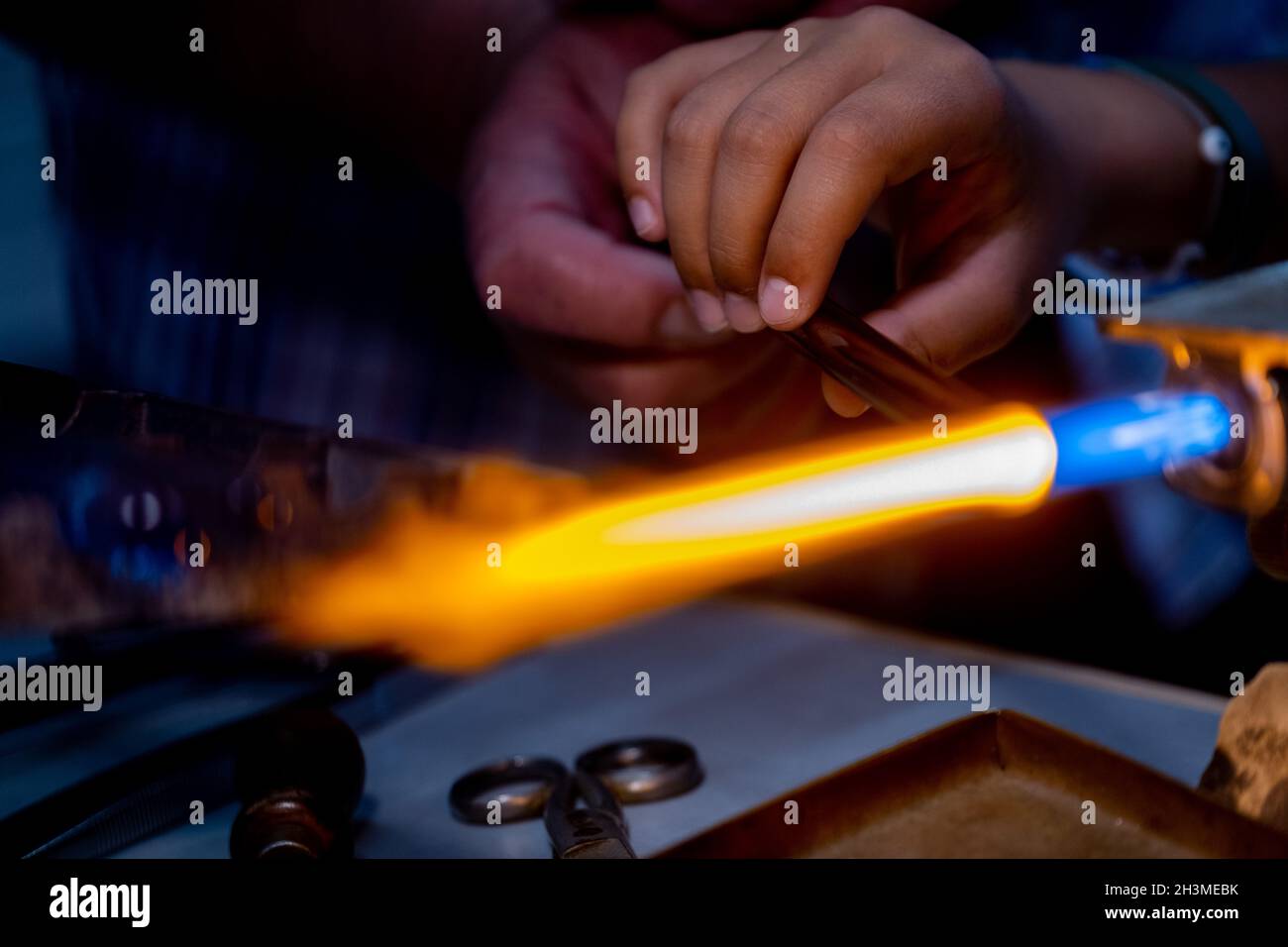 In einer Glasfabrik in Murano lehrt ein älterer Flammenarbeiter einem Kind, wie man das Glas arbeitet.Venedig, Italien 14. Juni 2021.(MVS) Stockfoto