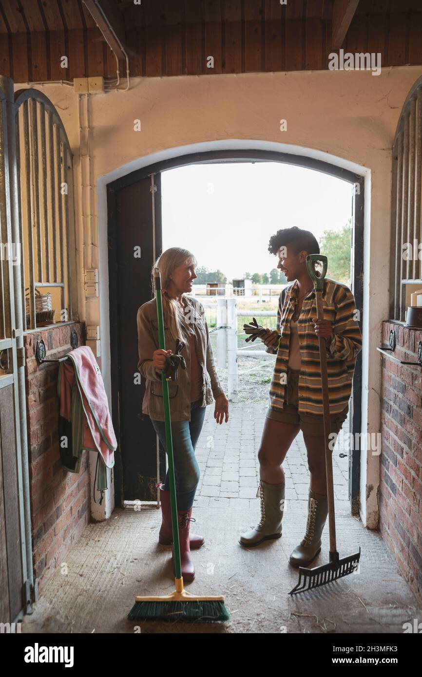 Lächelnde Mutter und Tochter sprechen im Stall Stockfoto