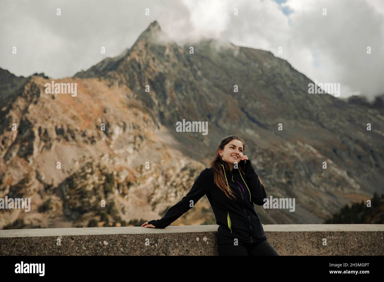 Mädchen am Telefon mit einigen Bergen im Hintergrund sprechen Stockfoto