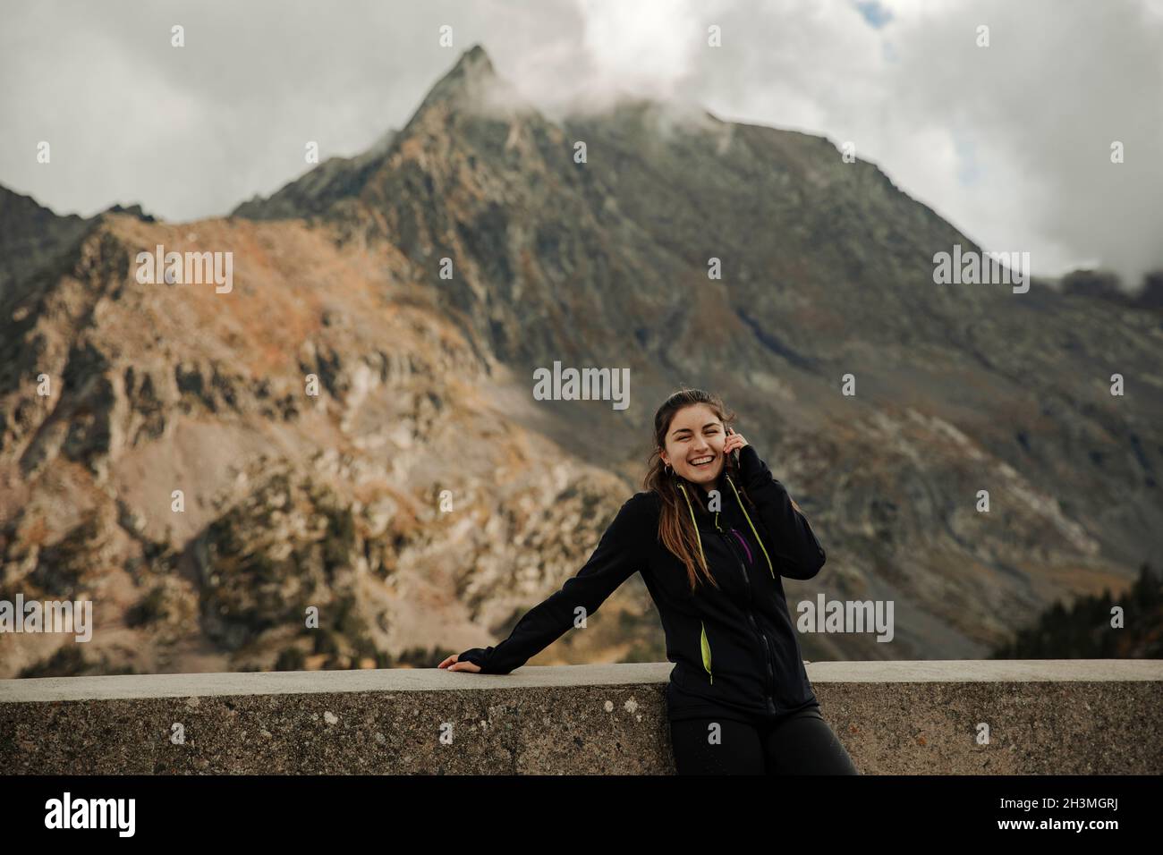 Mädchen am Telefon mit einigen Bergen im Hintergrund sprechen Stockfoto