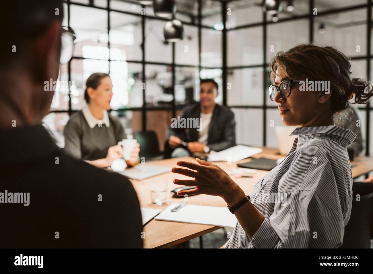 Weibliche Unternehmerin mit mittlerem Erwachsenen, die im Vorstandszimmer mit einer Kollegin diskutiert Stockfoto