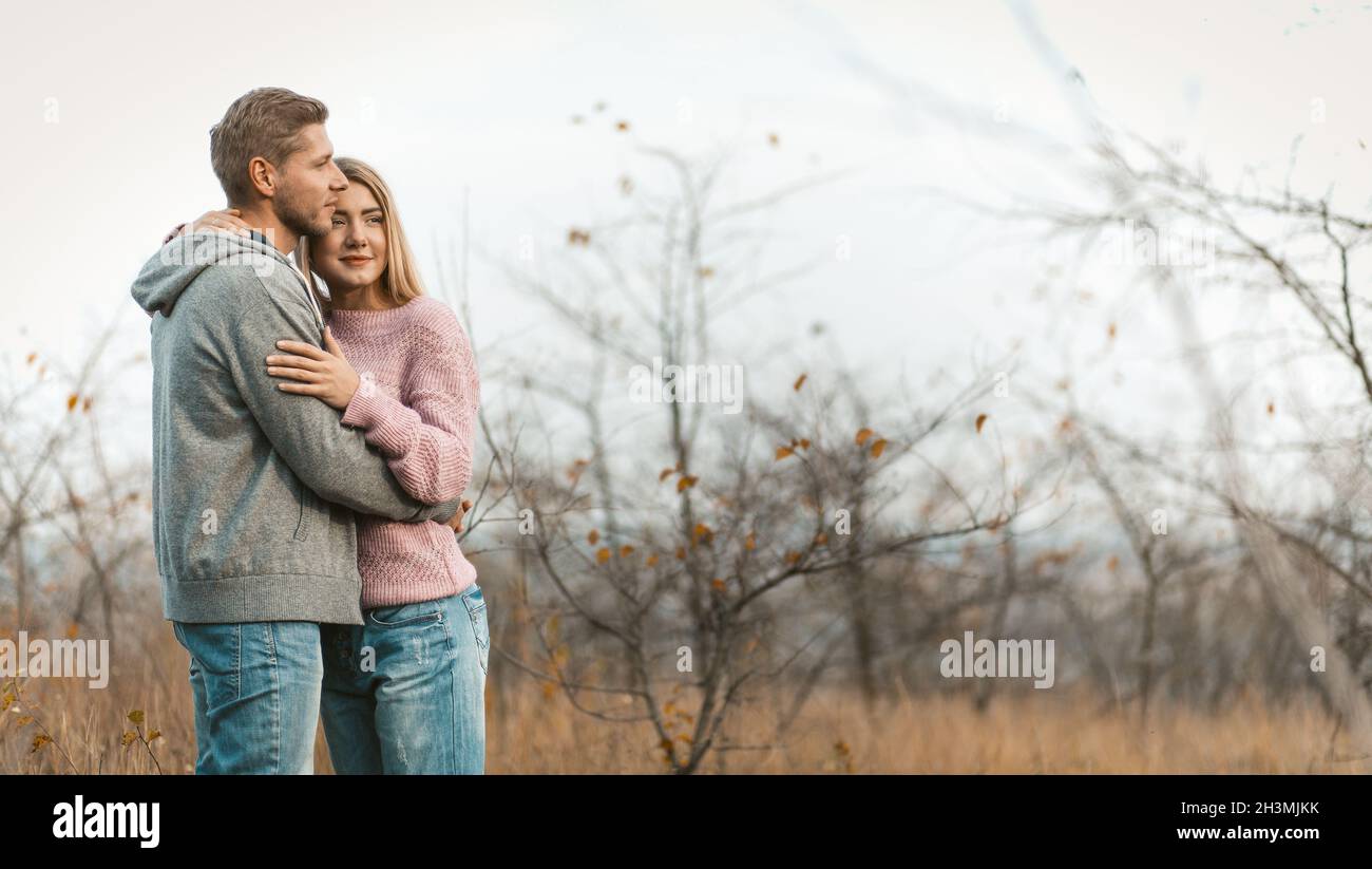Liebevolles Paar, das sich auf einem Hintergrund der herbstlichen Naturlandschaft ausruhen und umarmen kann. Junge kaukasische Mann und Frau huggin Stockfoto