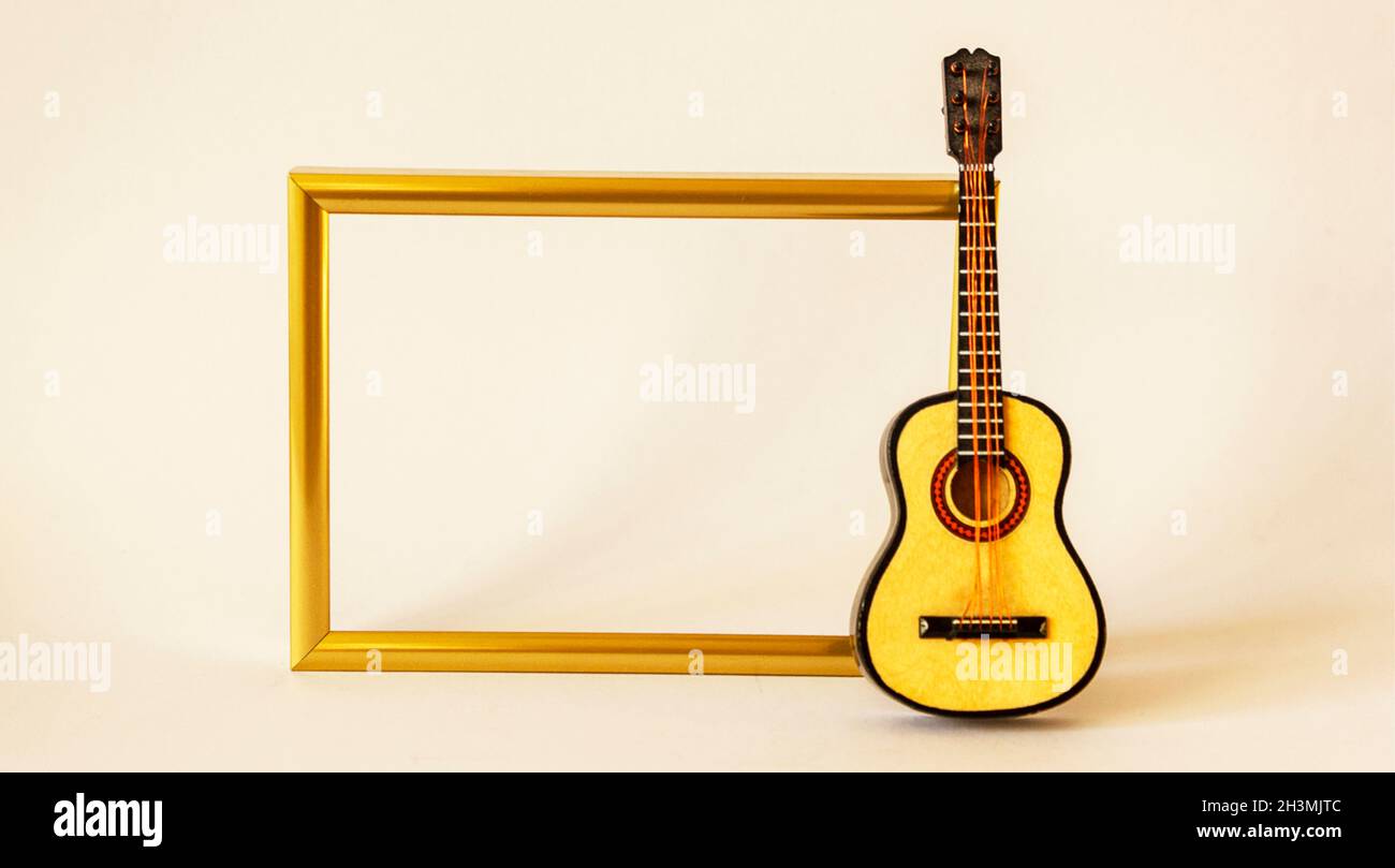 Dekorativer Goldrahmen für Foto oder Aufnahme mit Gitarre auf weißem Hintergrund Stockfoto