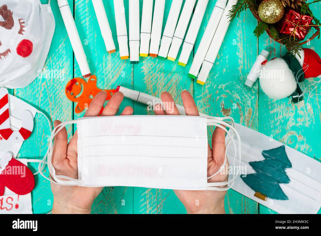 Weihnachten inmitten einer Pandemie feiern. Wir zeichnen Bilder und Inschriften auf medizinische Masken. Kinderkunstprojekt Stockfoto