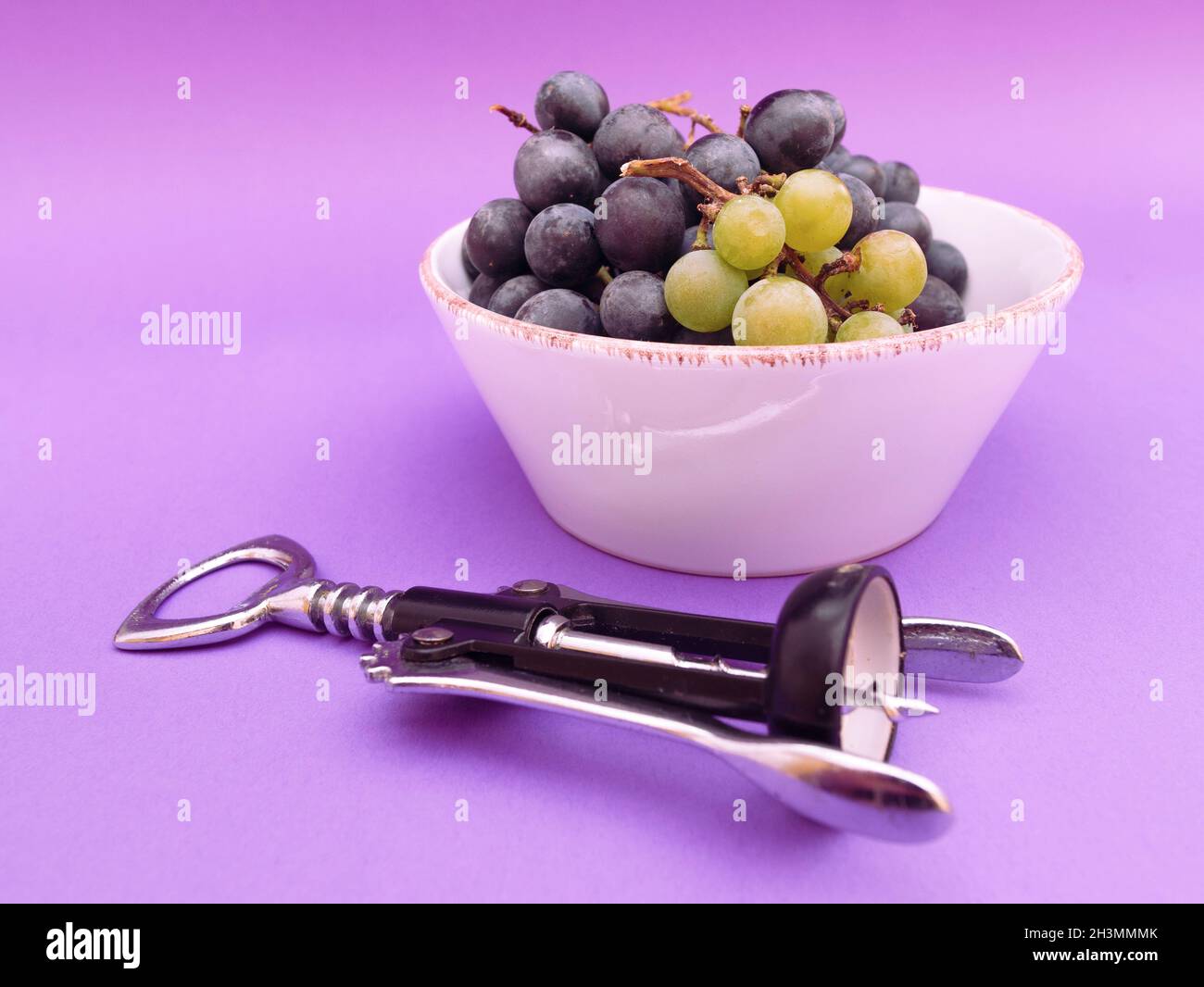 Rotwein und weiße Trauben und Korken auf violettem Hintergrund, Foto Stockfoto