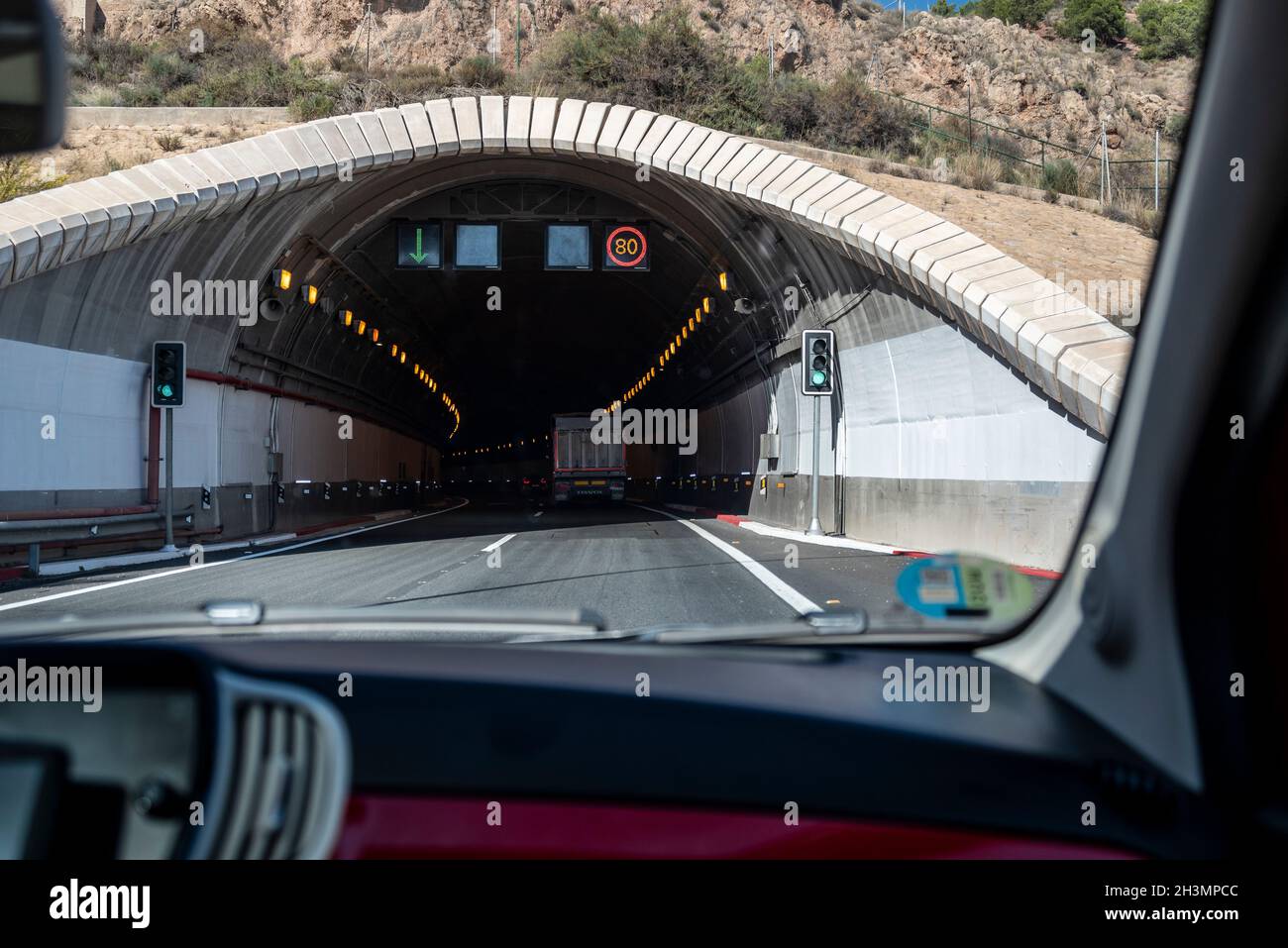 Fahrt in den Tunnel de Lorca, A-7 Straßentunnel in Lorca, Region Murcia, Spanien. Innenansicht des Tunneleingangs mit Lastwagen, Geschwindigkeitsbegrenzung Stockfoto