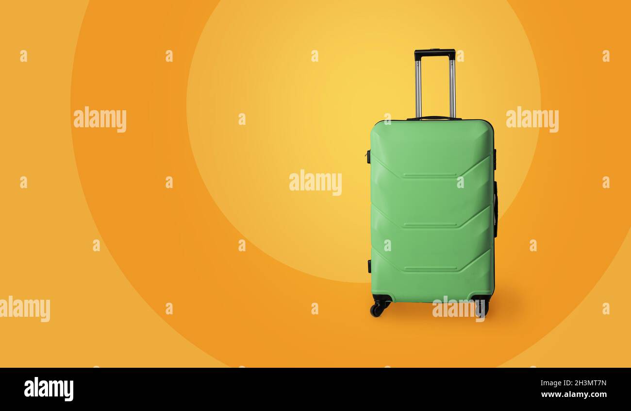 Reisegepäck Koffer. Grüner Plastikkoffer mit Rädern und ausziehbarem Teleskopgriff isoliert auf gelbem Hintergrund. Auto Stockfoto