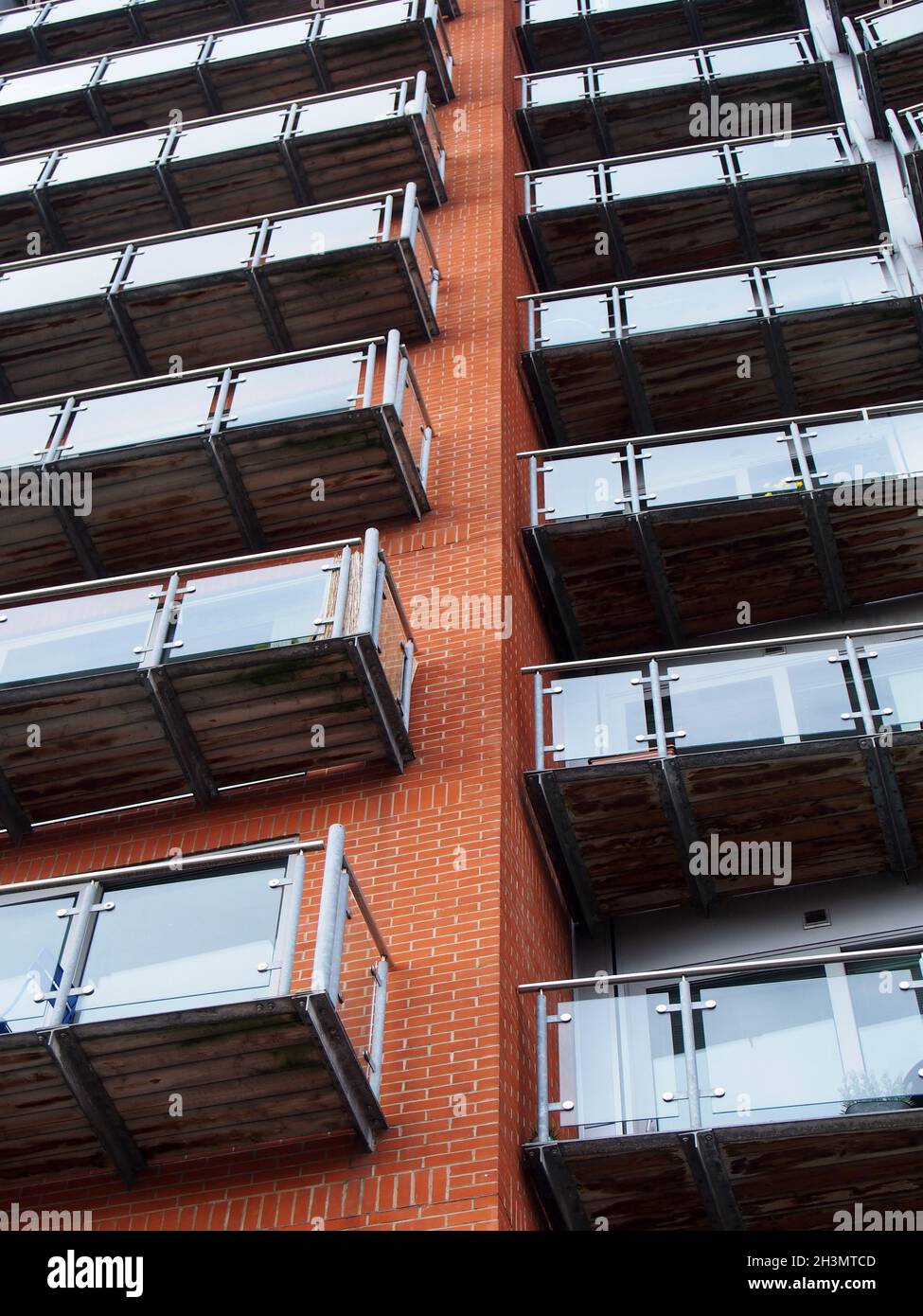 Blick auf ein modernes Apartmentgebäude mit Fenstern in Ziegelwänden und Glasbalkonen Stockfoto