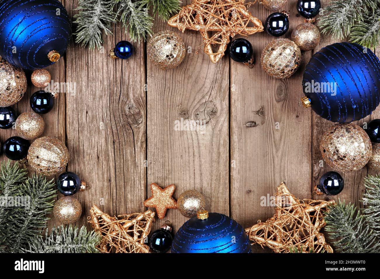 Weihnachtsrahmen mit dunkelblauen und goldenen Ornamenten und Baumzweigen. Oben auf einem alten Holzhintergrund. Stockfoto