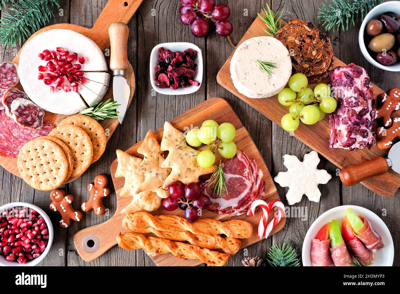 Weihnachtliche Tischszene mit Charcuterie vor dunklem Holzhintergrund. Auswahl an Käse- und Fleischgerichten. Draufsicht. Stockfoto