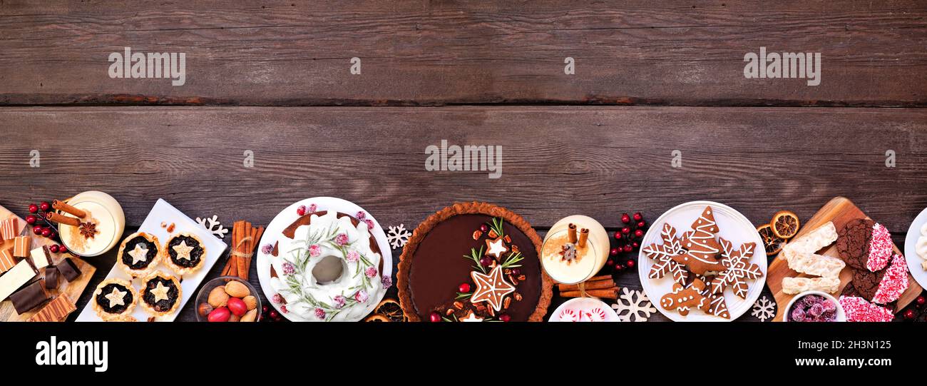 Auswahl an Weihnachtsdesserts und Süßigkeiten. Draufsicht unterer Rand über einem Holzbanner Hintergrund. Bundt-Kuchen, Schokoladenkuchen, Hackeetörtchen, Stockfoto