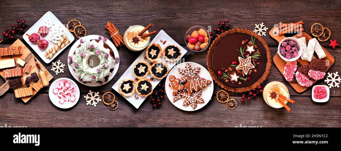 Verschiedene Weihnachtsdesserts und Süßigkeiten. Panorama-Tischszene von oben auf einem rustikalen Holzhintergrund. Bundt-Kuchen, Schokoladenkuchen, Hacktektar Stockfoto