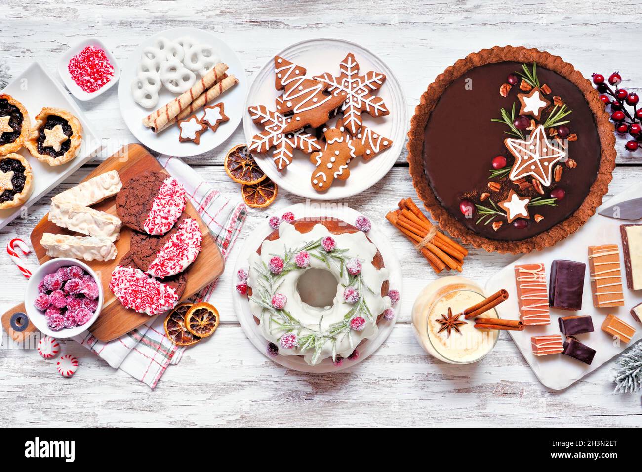 Auswahl an Weihnachtsdesserts und Süßigkeiten. Oben sehen Sie eine Tischszene auf einem weißen Holzhintergrund. Bundt-Kuchen, Schokoladenkuchen, Hackbratkuchen, coo Stockfoto