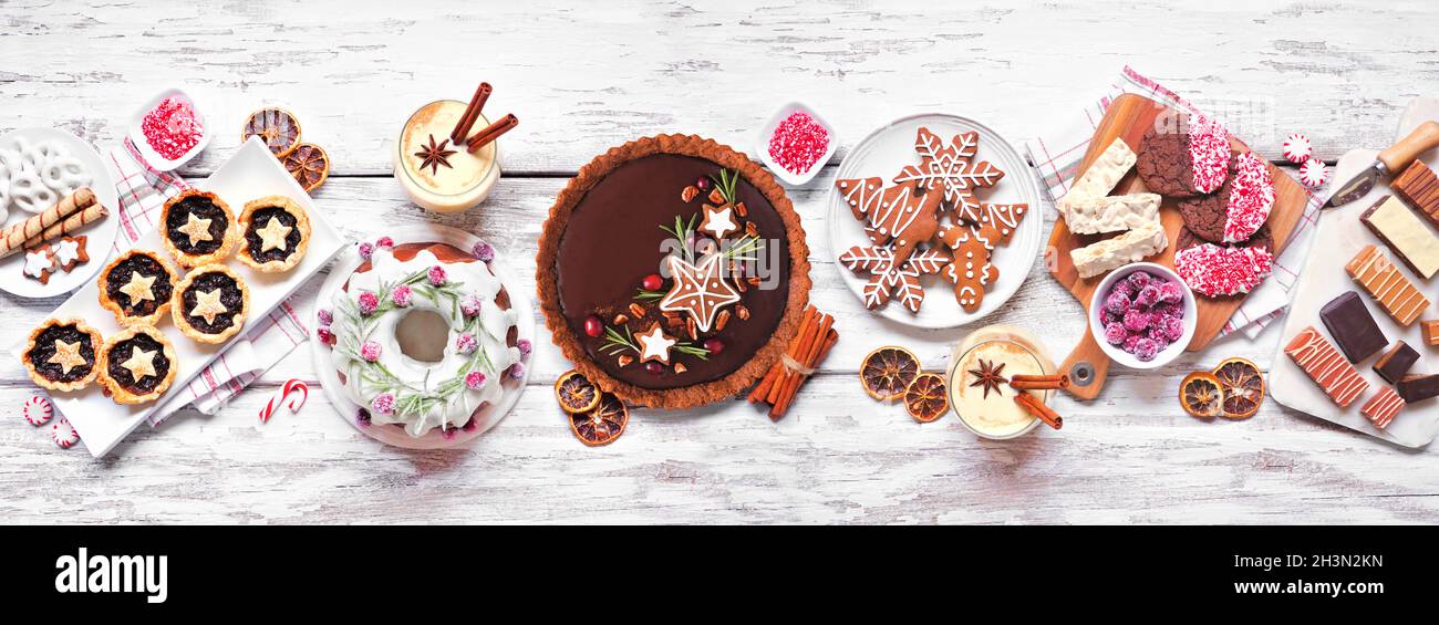 Verschiedene weihnachtliche Desserts und Süßigkeiten. Von oben gefaßtes Tischbild auf weißem Holzbanner-Hintergrund. Bundt-Kuchen, Schokoladenkuchen, Hackeetörtchen Stockfoto