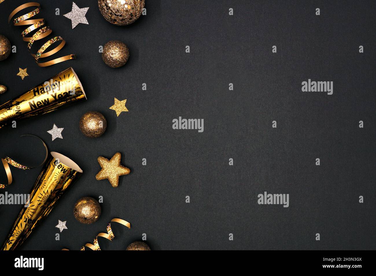 Silvester Seitenrand von glitzernden goldenen Sternen, Luftschlangen, Dekorationen und Geräuschmachern. Draufsicht auf schwarzem Hintergrund. Stockfoto