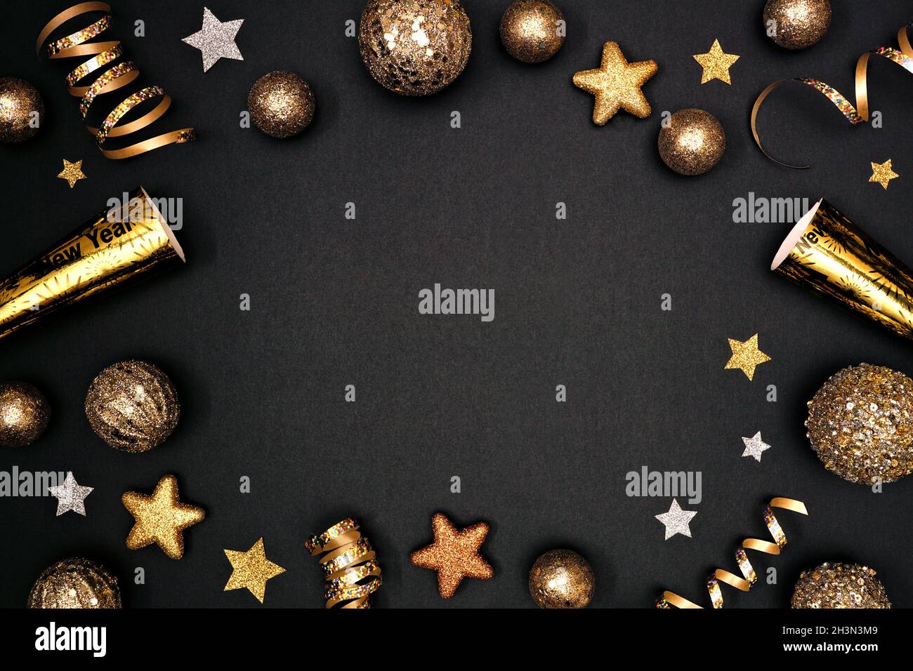 Silvester Rahmen aus glitzernden goldenen Sternen, Luftschlangen, Dekorationen und Geräuschmachern. Oben auf schwarzem Hintergrund. Stockfoto