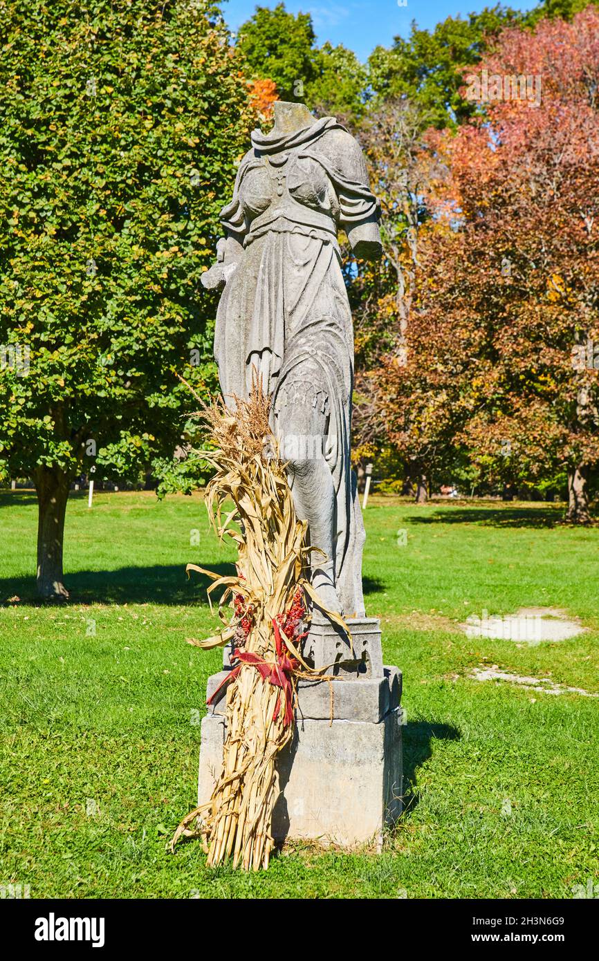 Kopflose Steinstatue im Herbst mit Herbstdekor im Grasfeld Stockfoto