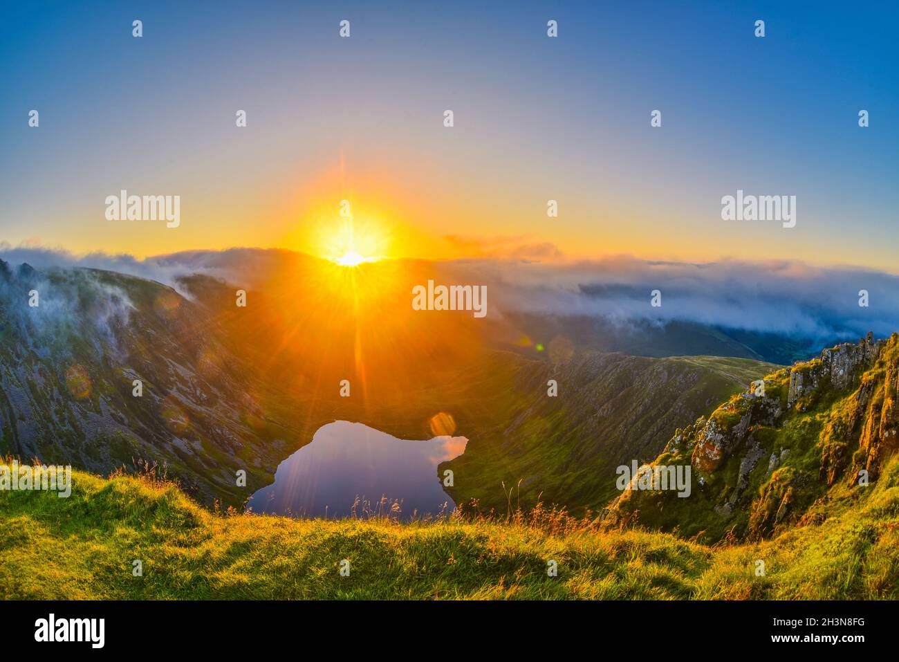 Erstaunlicher Sonnenaufgang auf dem Cadair Idris Berg in Snowdonia, Nordwales. Die Sonne scheint auf dem Gletschersee, die herrliche Wolkeninversion, die Berge umhüllt. Stockfoto