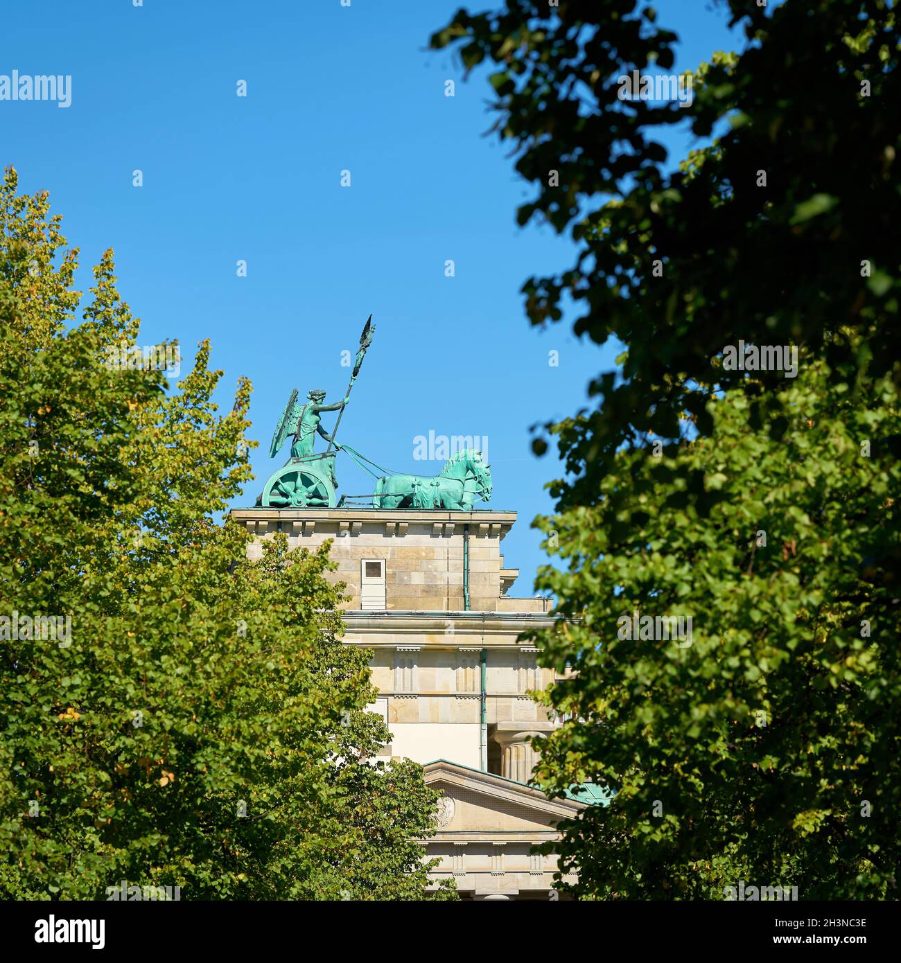 Quadriga am Brandenburger Tor in Berlin durch eine Spalt zwischen Straßenbäumen Stockfoto