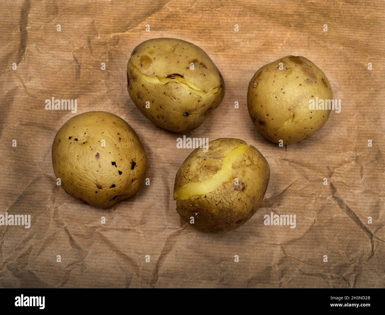 Vier gekochte Kartoffeln auf rohem braunem Papier Stockfoto